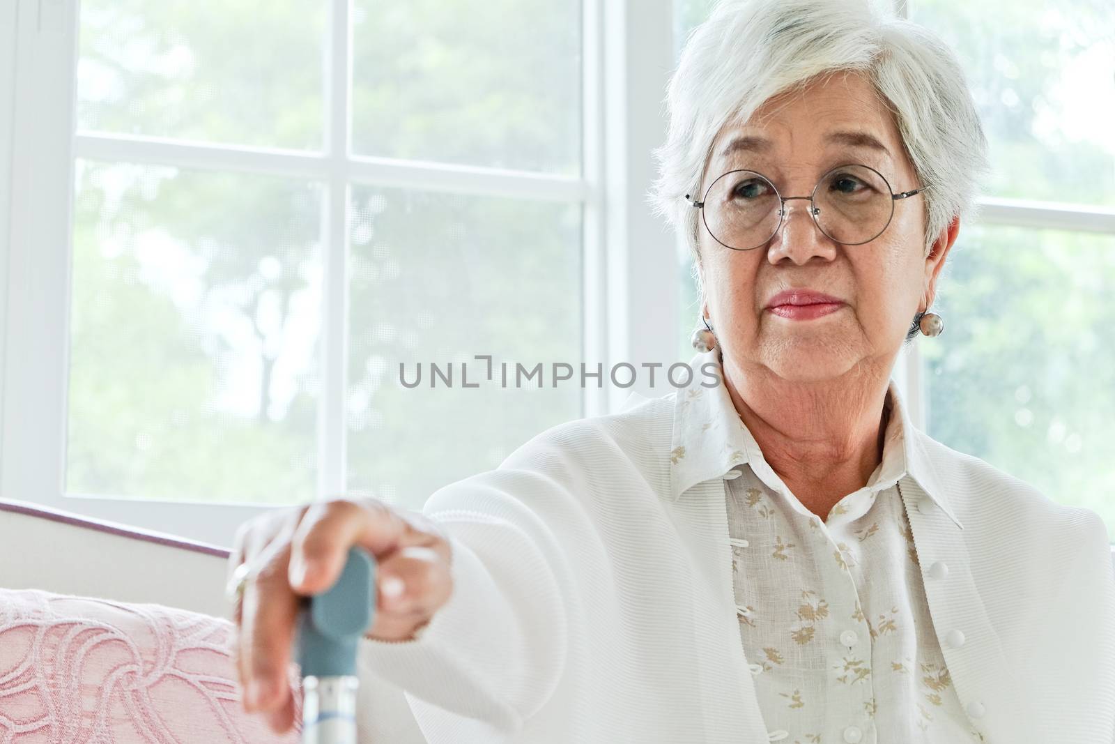 senior woman portrait, senior woman sitting alone on a sofa at home in a lonely mood.