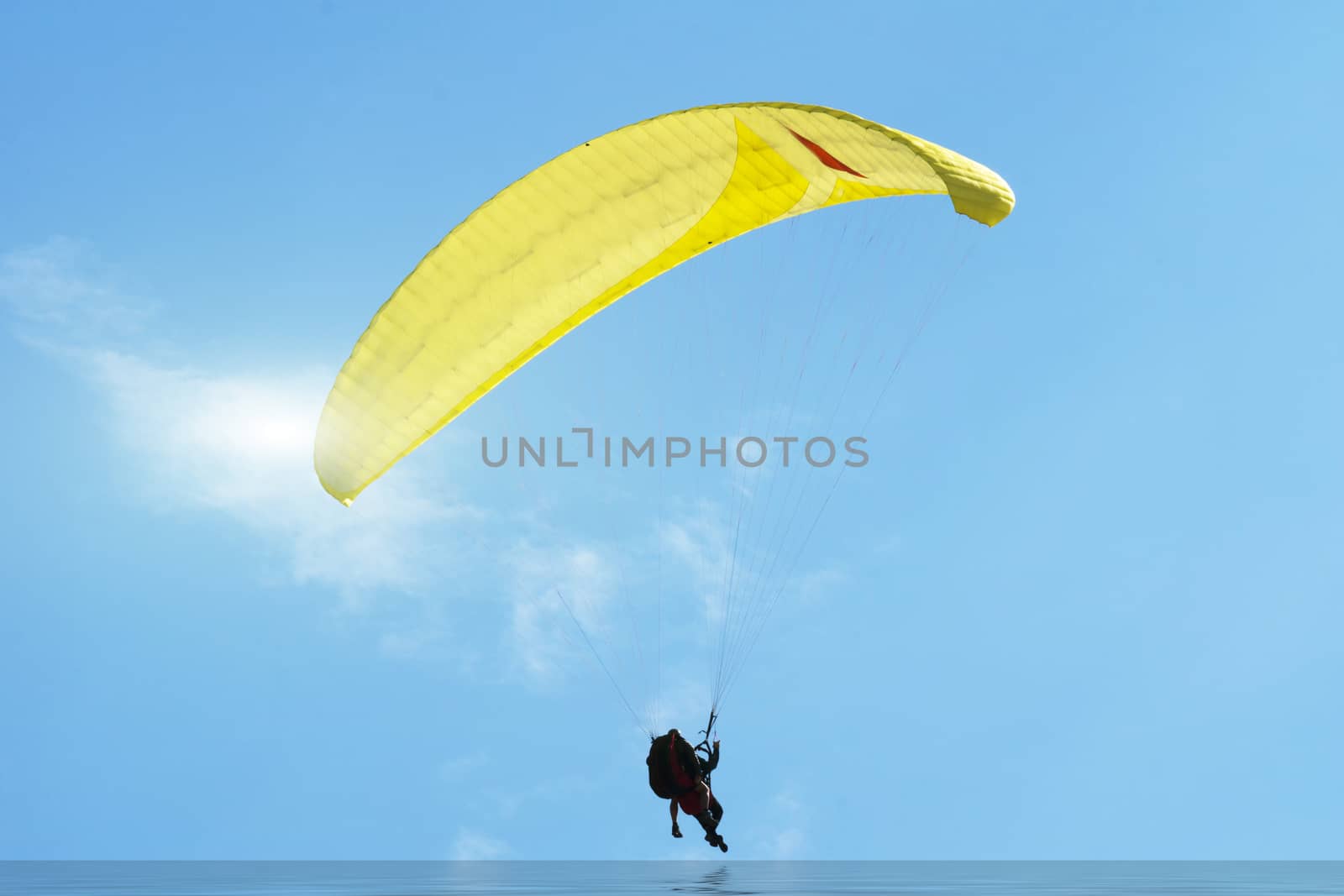 Paragliding over the Danish North Sea coastline on blue sky background