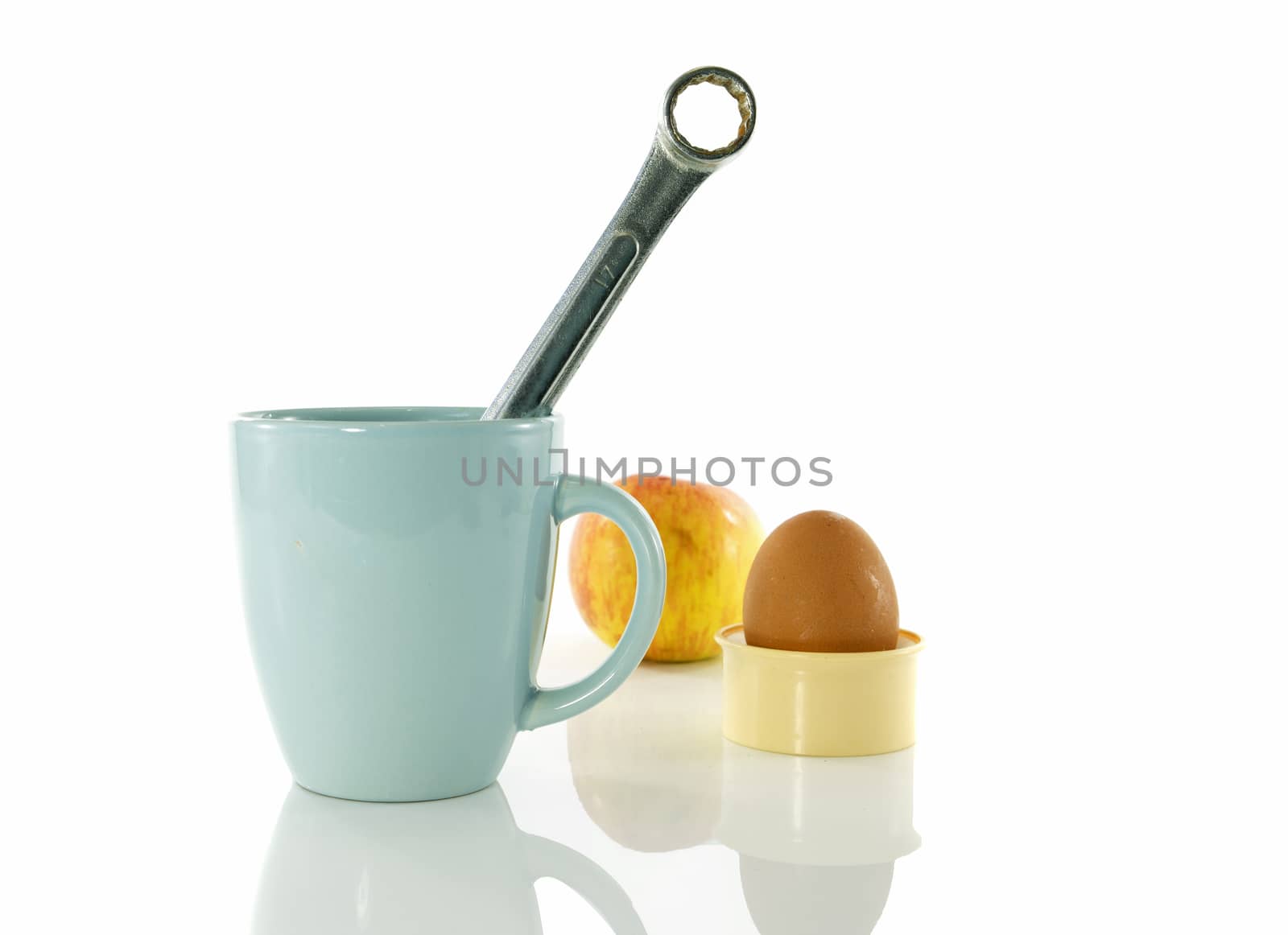time for a coffee break during work with blue coffe cup and metal boxwrench or spanner with apple and egg as background  isolated on white