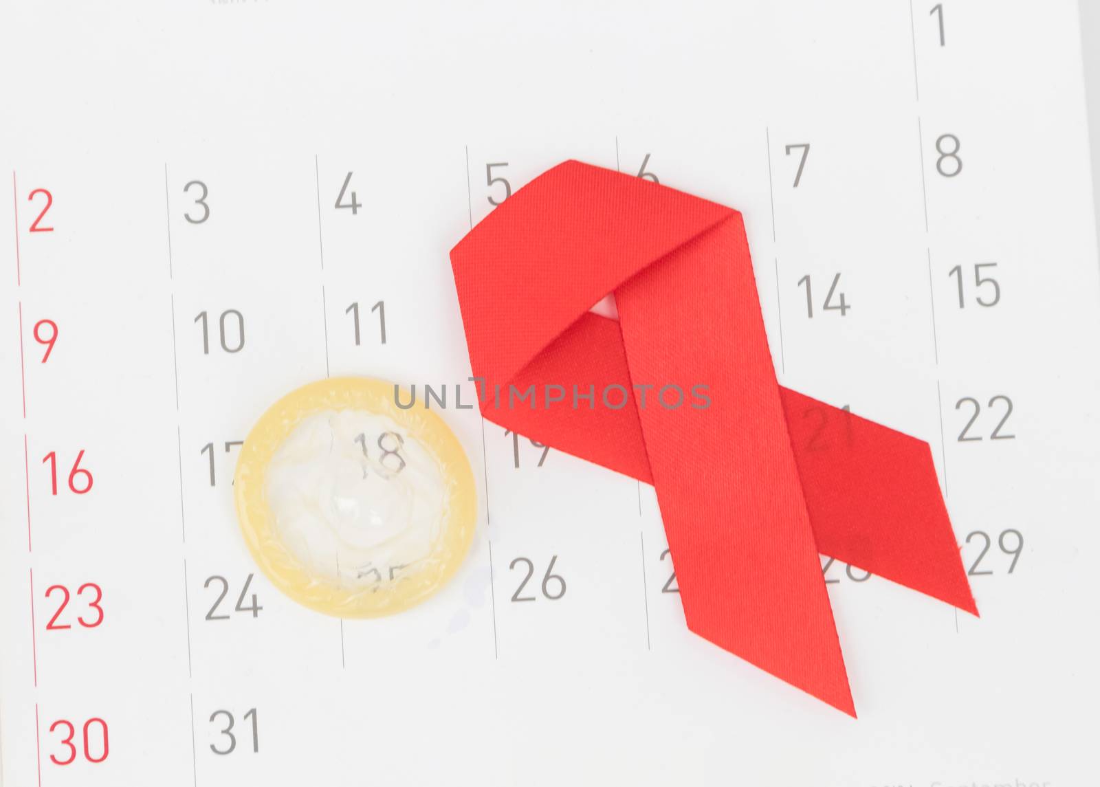 Closeup condom and red ribbon with calendar background for AIDs awareness concept