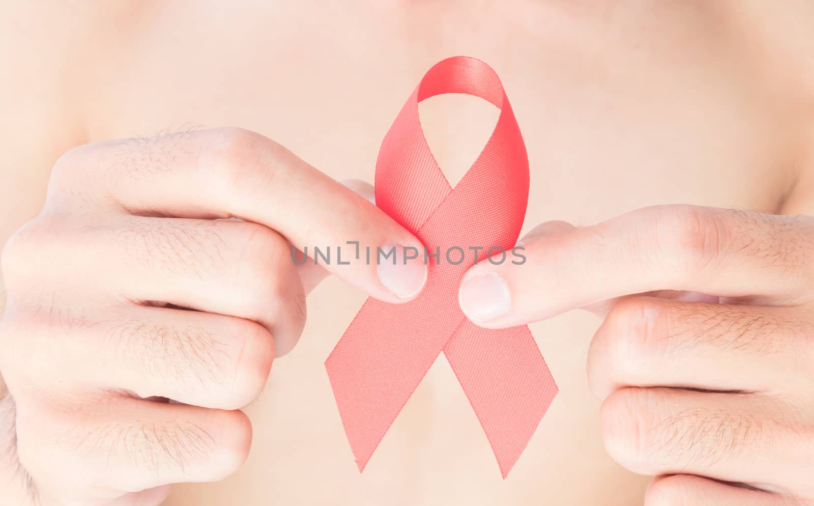 Hand hold red ribbon with blurred man background for AIDs by pt.pongsak@gmail.com