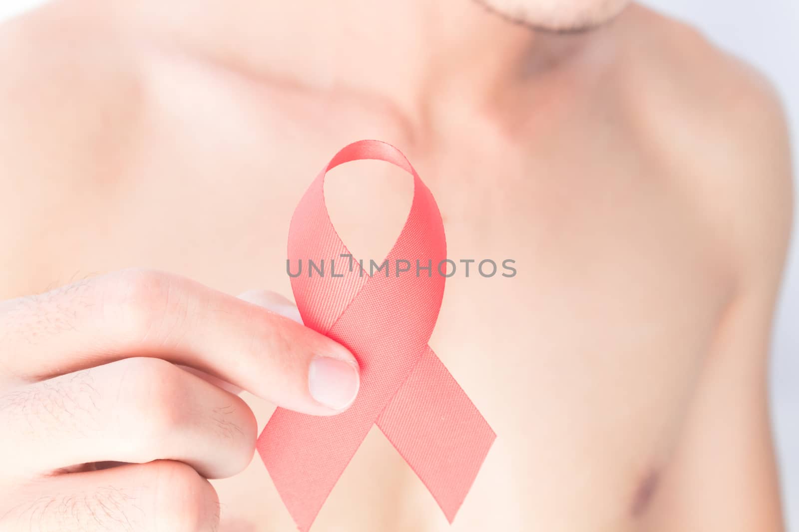 Hand hold red ribbon with blurred man background for AIDs awareness concept