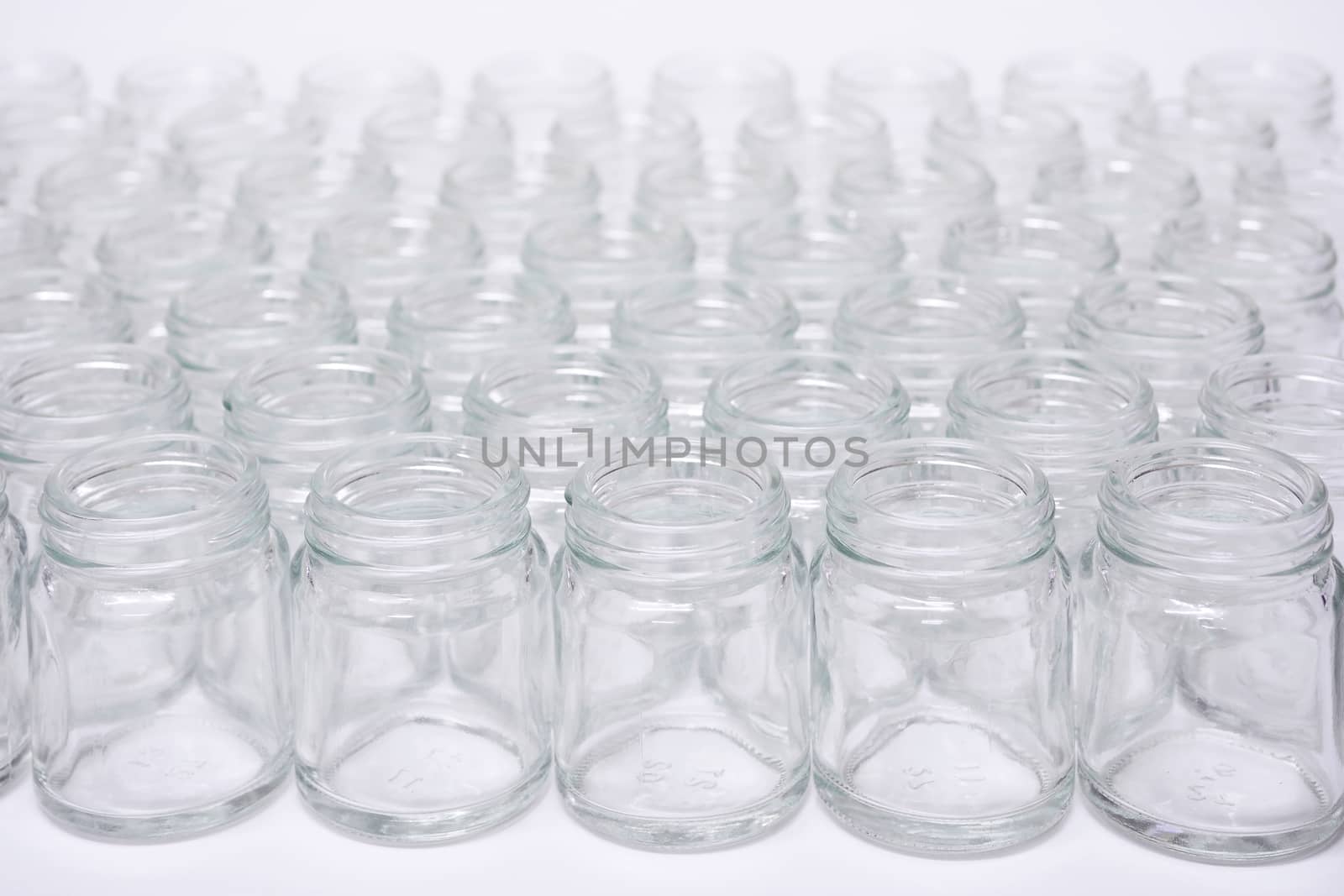 Short glass bottle no cap many glasses row, on white background.