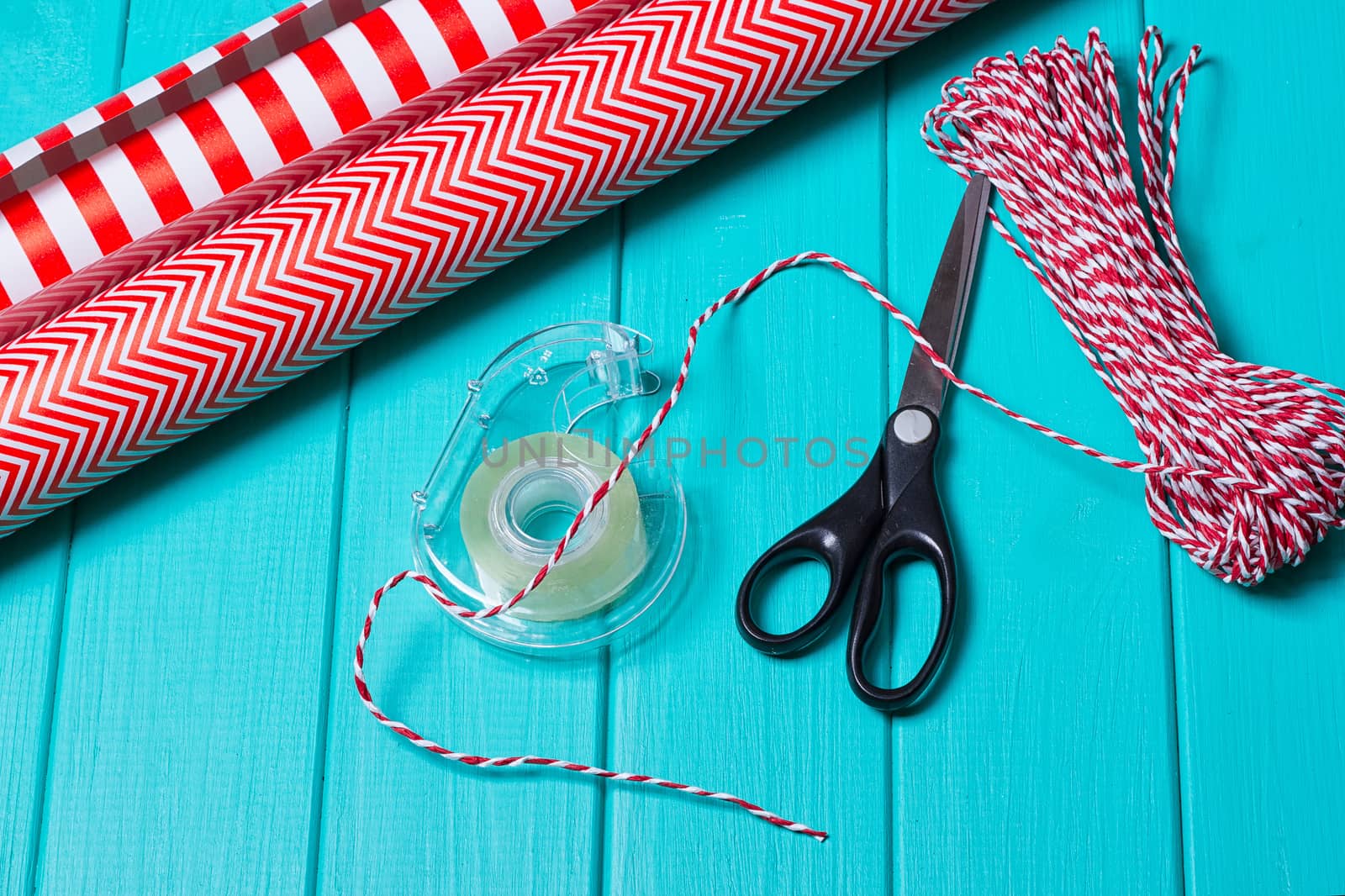 Christmas Gift Wrapping Party Time with Colorful Paper, Ribbon Bows, Scissors and Tape on Cyan Blue Shabby Chic Wood Board Background Space for copy, text