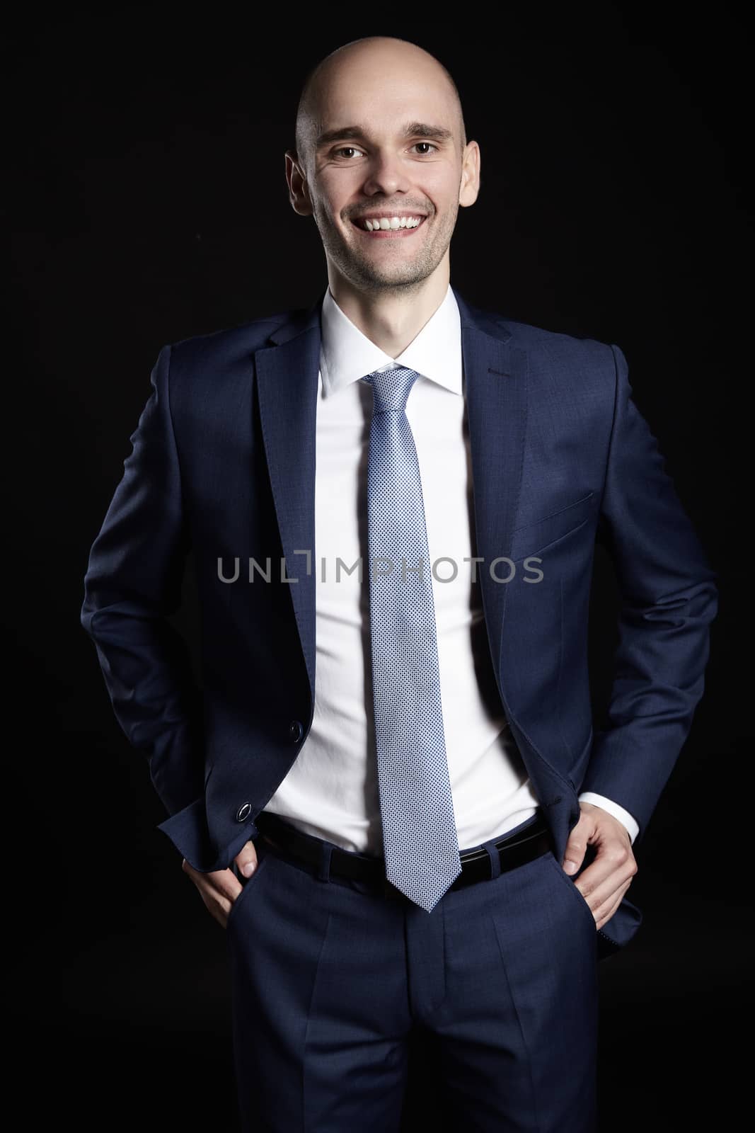 Portrait of cheerful businessman on black background.