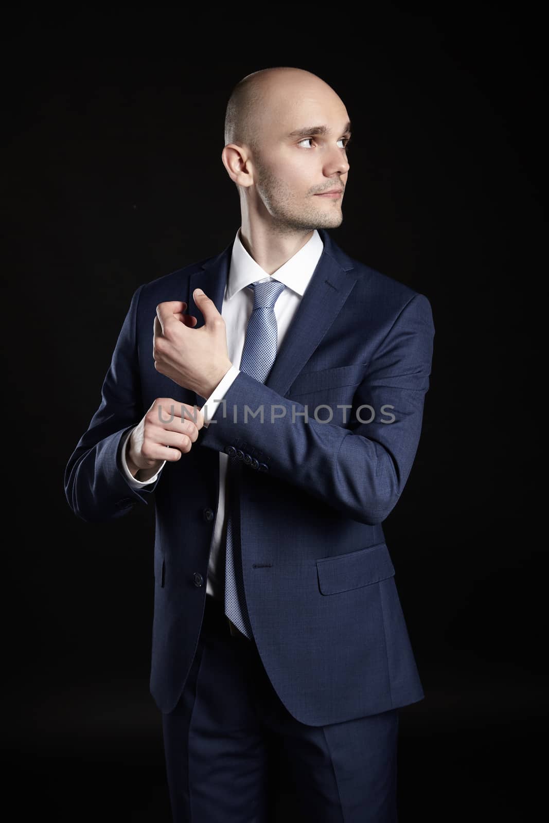 Studio shot of elegant man fixing cuffs his button down shirt.