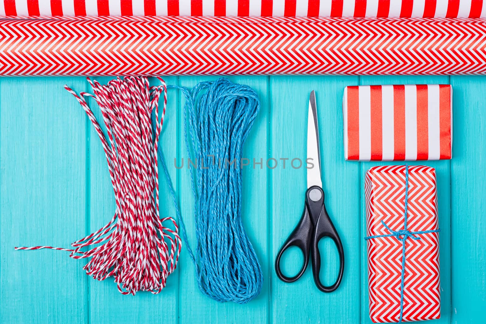 Christmas Gift Wrapping Party Time with Colorful Paper, Ribbon Bows, Scissors and Tape on Cyan Blue Shabby Chic Wood Board Background Space for copy, text