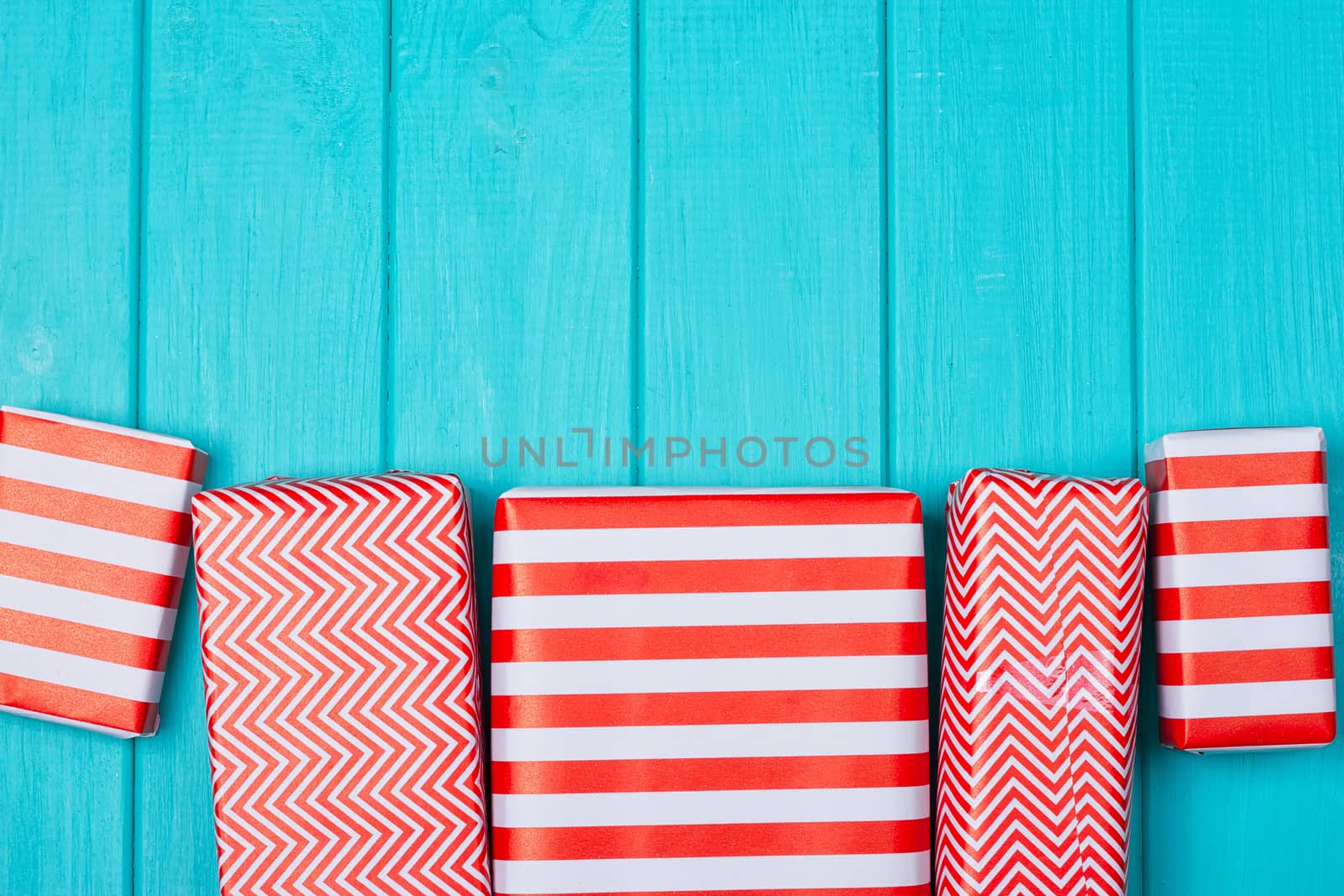 Many gifts in a red and white wrapper on a blue wooden background