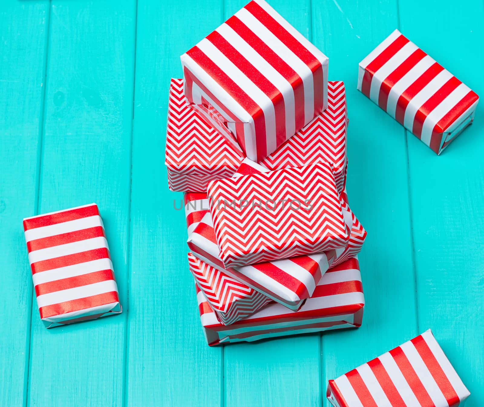 Many gifts in a red and white wrapper on a blue wooden background