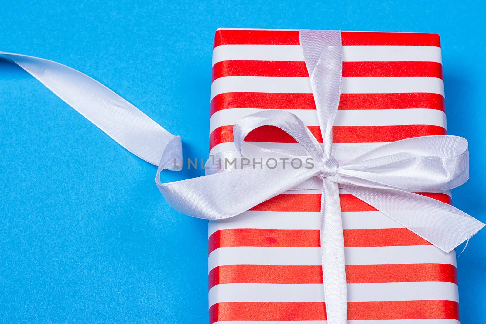 Gift in red and white packing with ribbon on a blue background. a Christmas gift