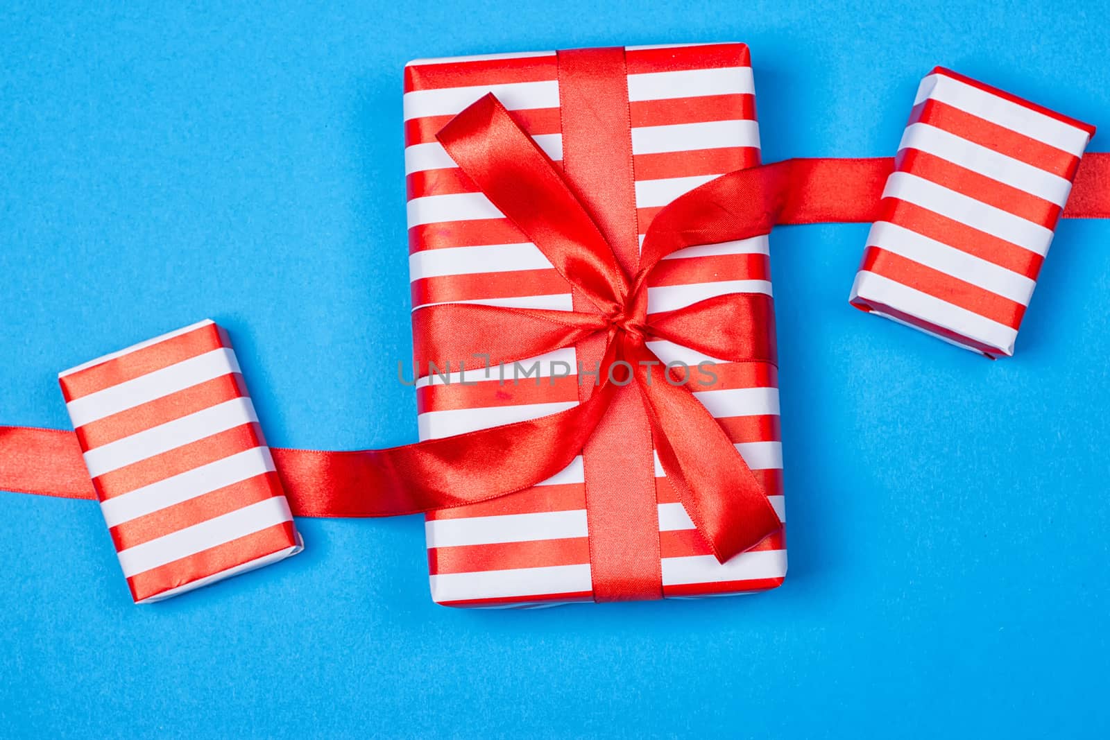 Several neatly laid out gifts in red packing on a blue background. Christmas presents