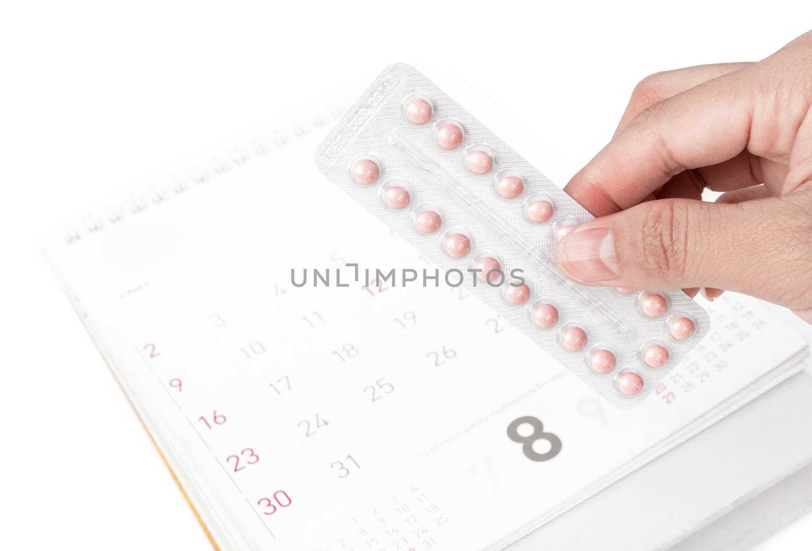 Close up hand hold birth-control pill with date of calendar background, health care and medicine concept