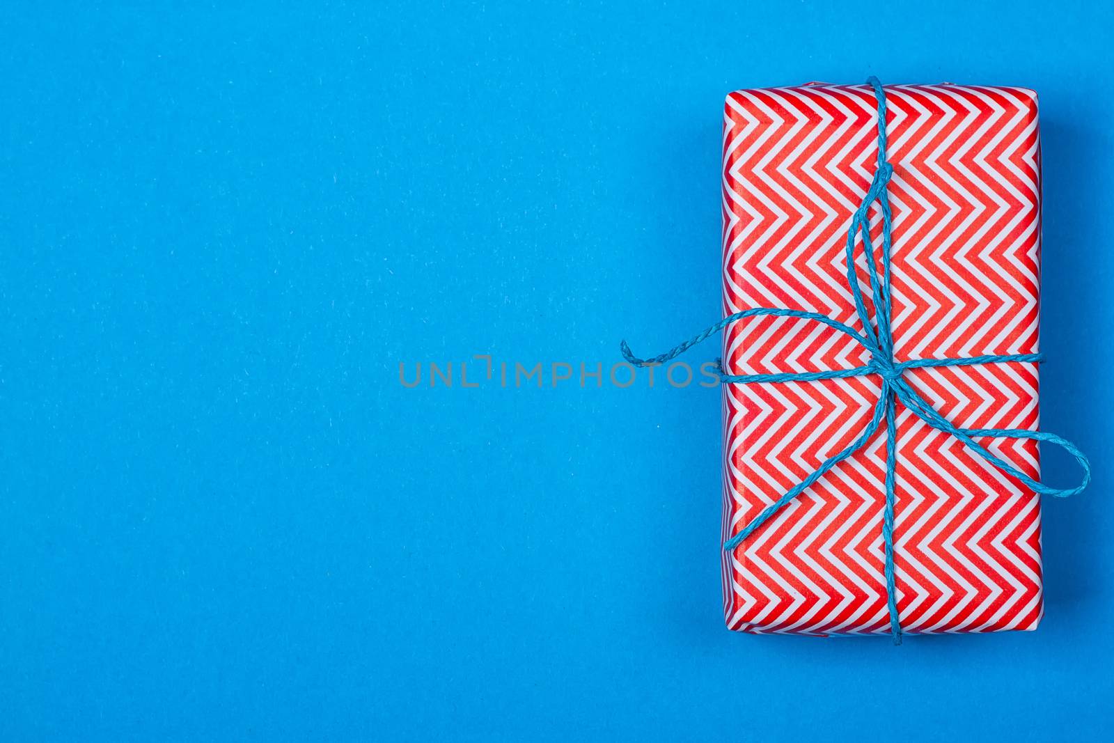 Gift in red and white packing with ribbon on a blue background. a Christmas gift