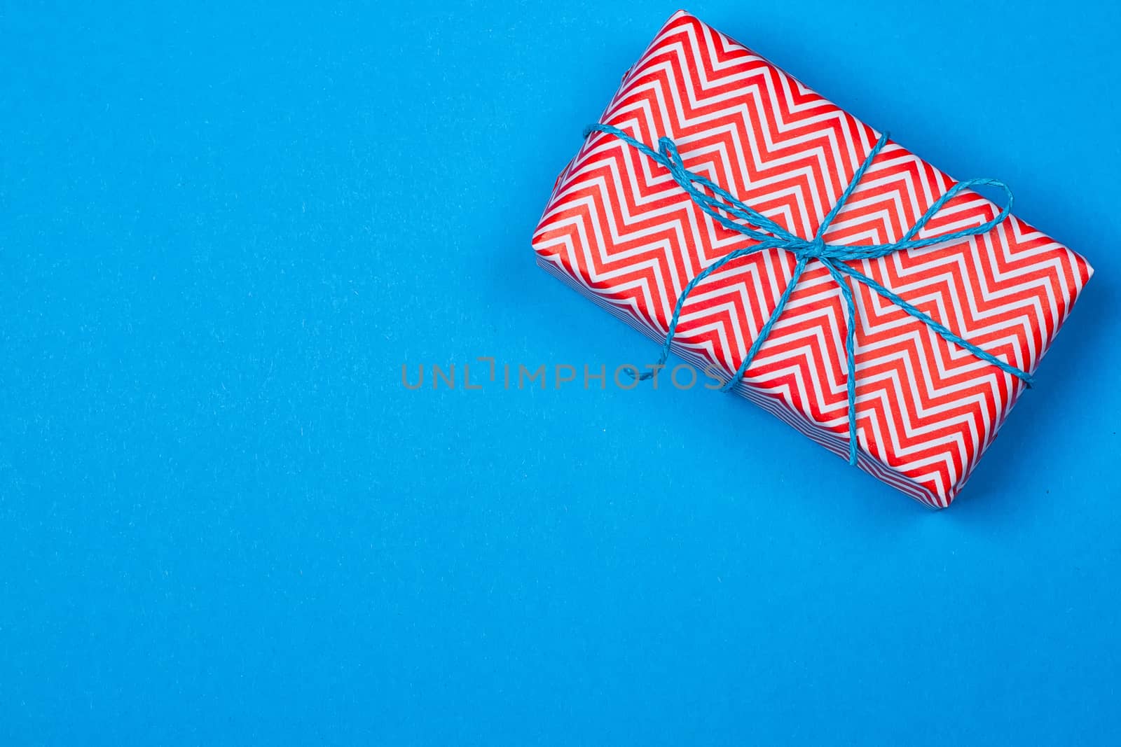 Gift in red and white packing with ribbon on a blue background. a Christmas gift