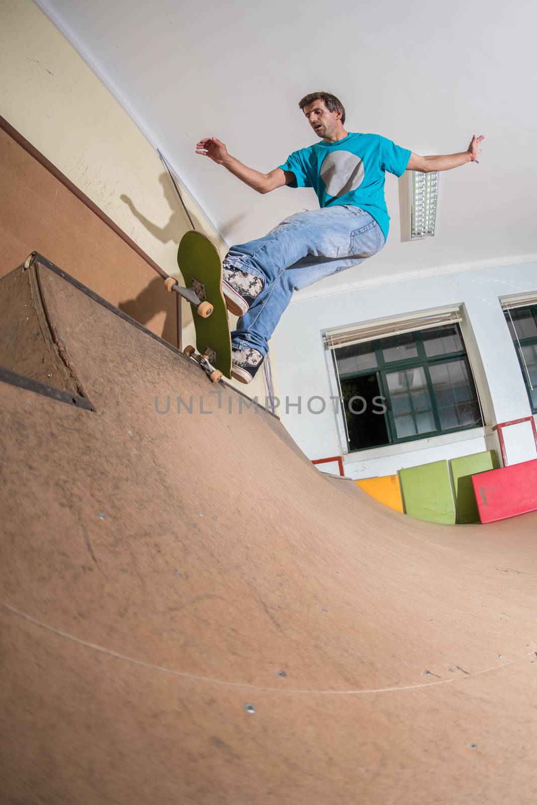 Skateboarder performing a trick on mini ramp at indoor skate park.