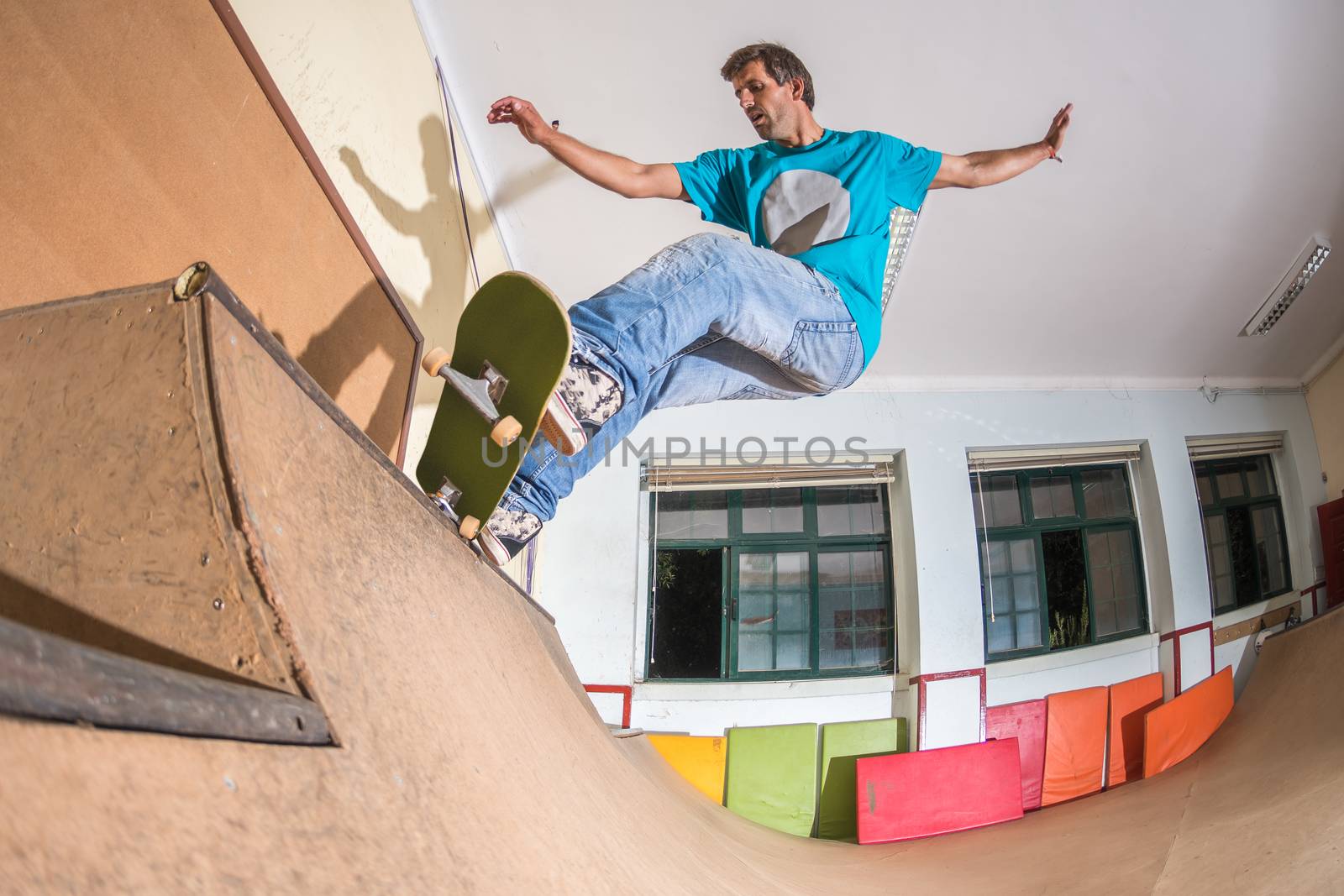 Skateboarder performing a trick on mini ramp at indoor skate park.