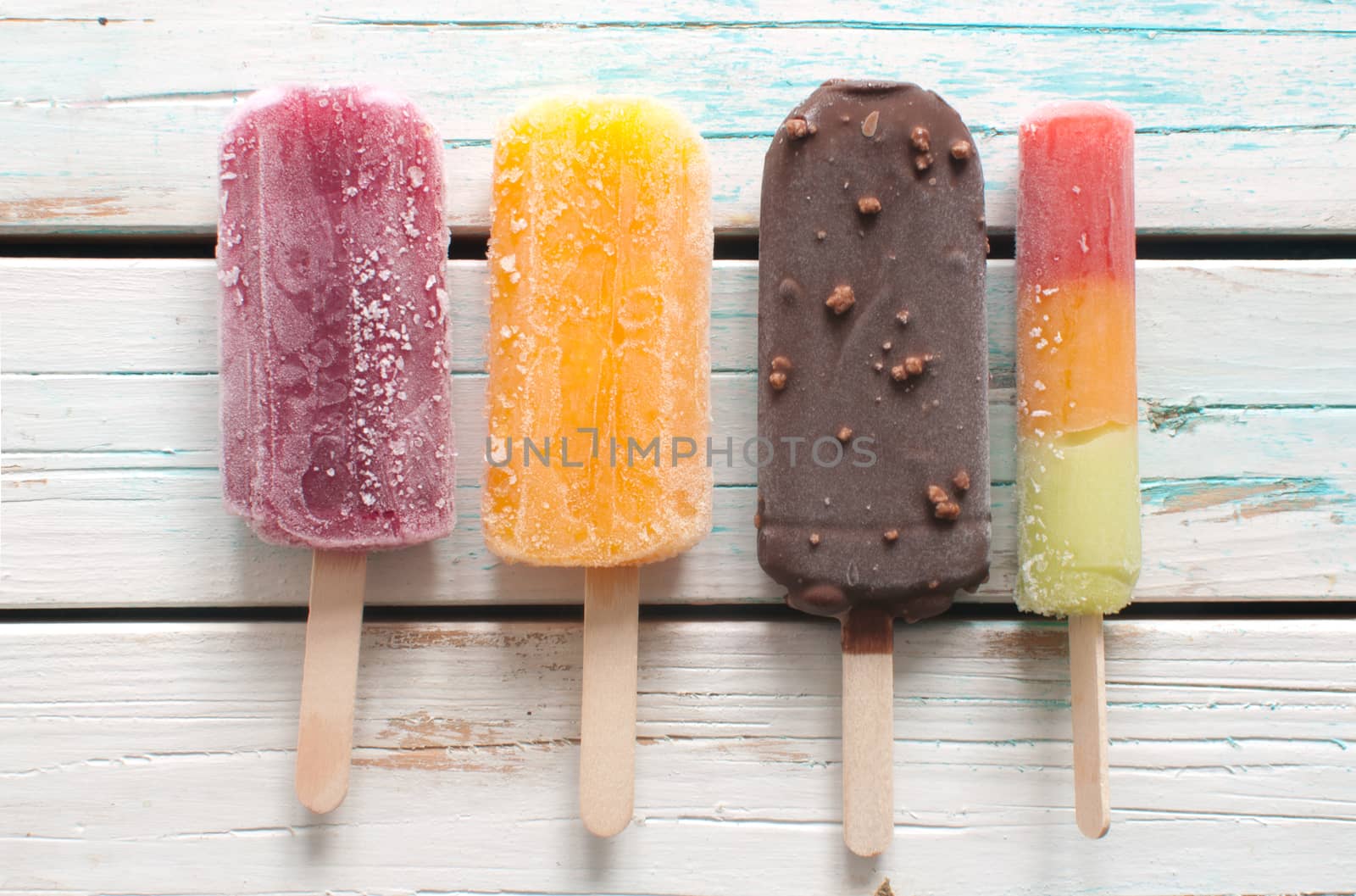 Assorted ice popsicles over wooden background