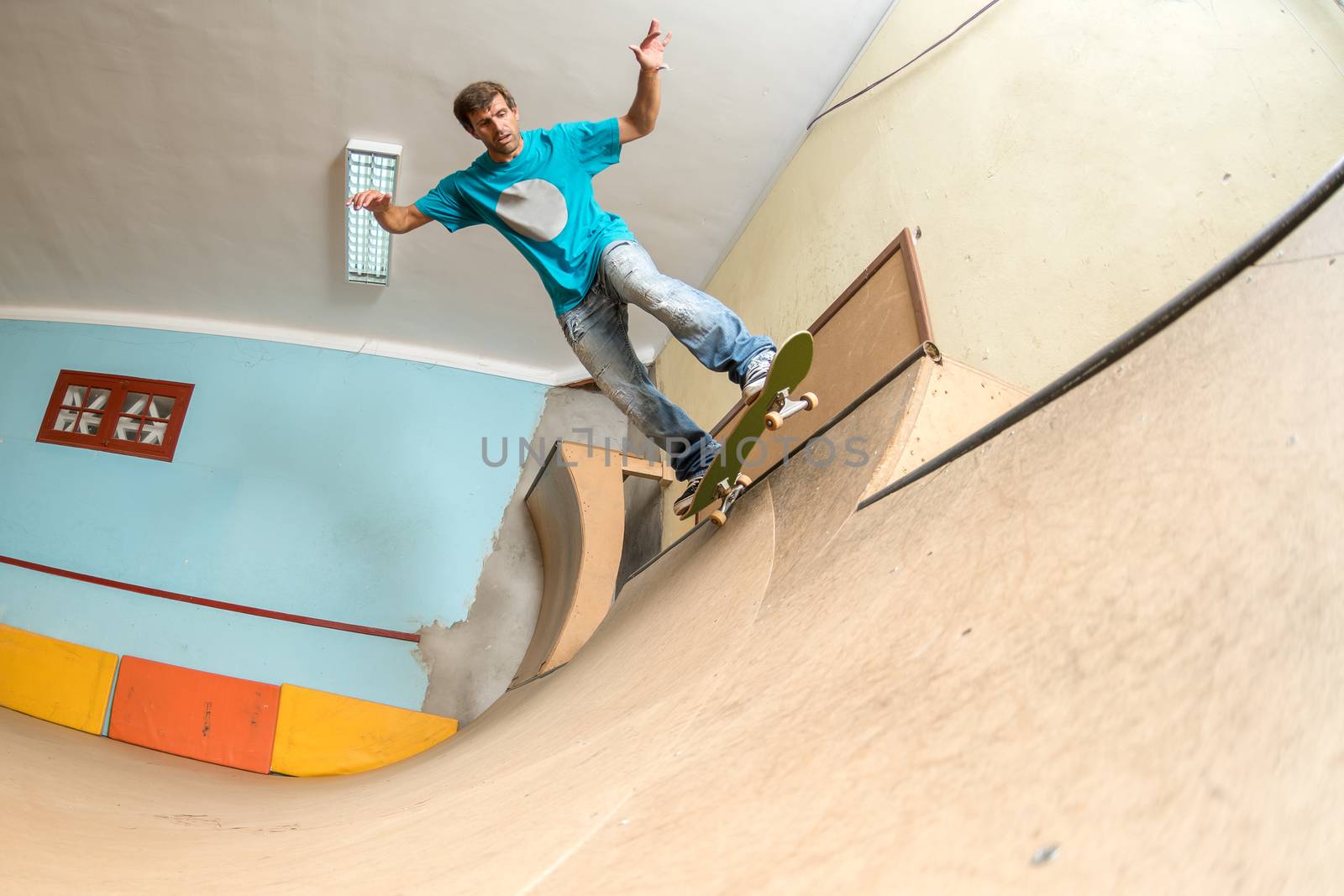 Skateboarder performing a trick on mini ramp at indoor skate park.