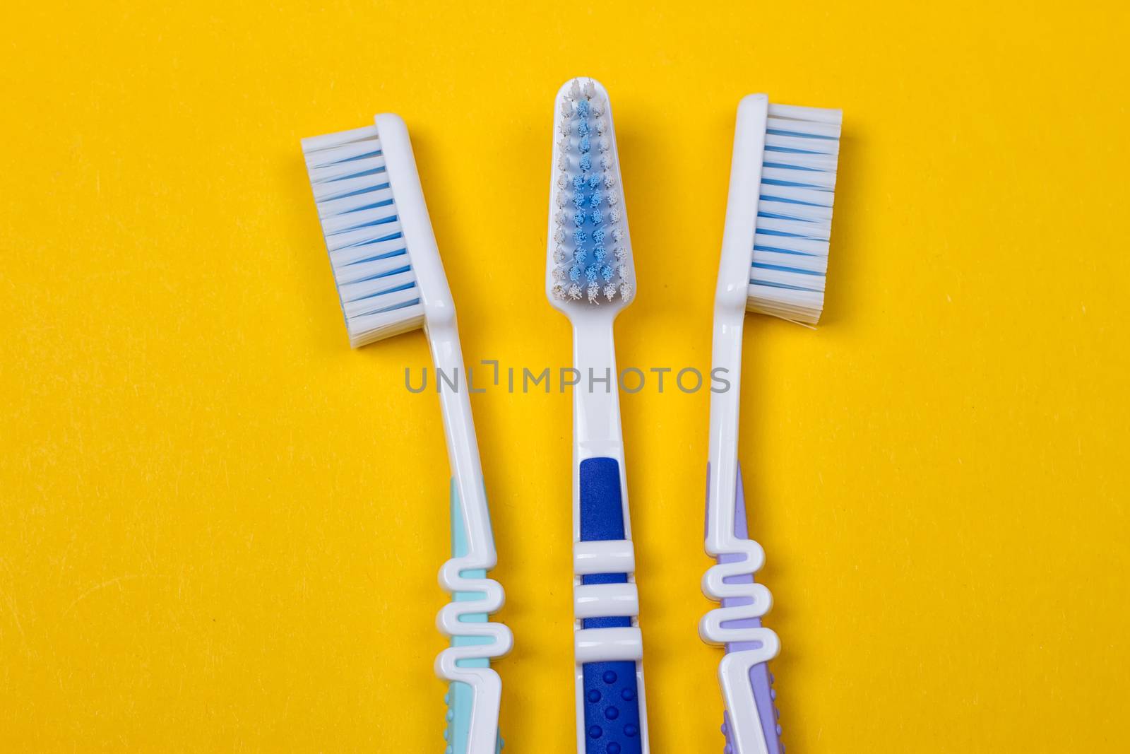 three Toothbrushes on the yellow background. Top view