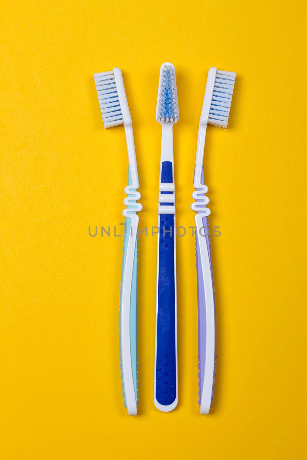 three Toothbrushes on the yellow background. Top view