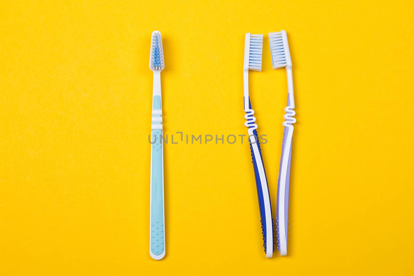 three Toothbrushes on the yellow background. Top view