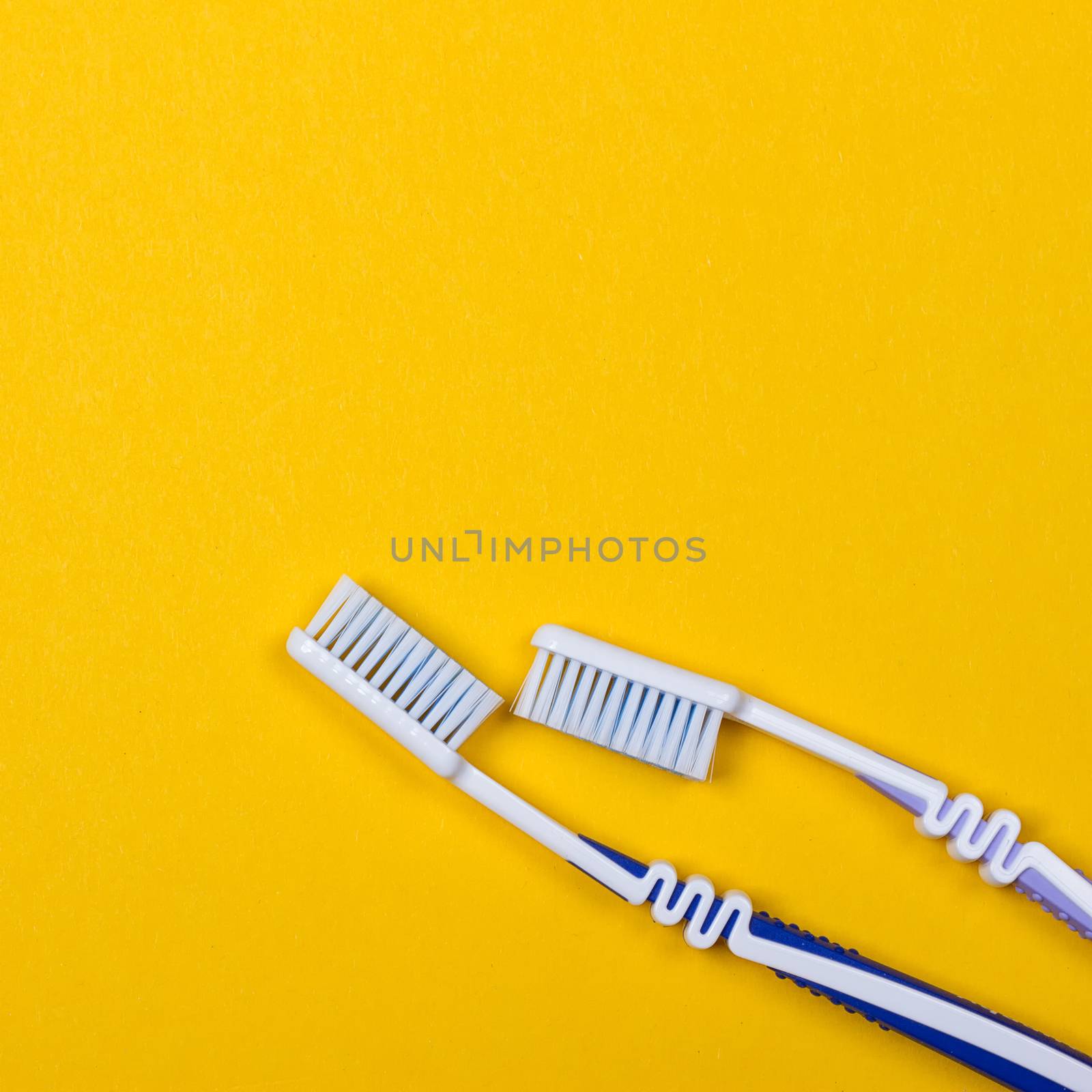 twi Toothbrushes on the yellow background. Top view