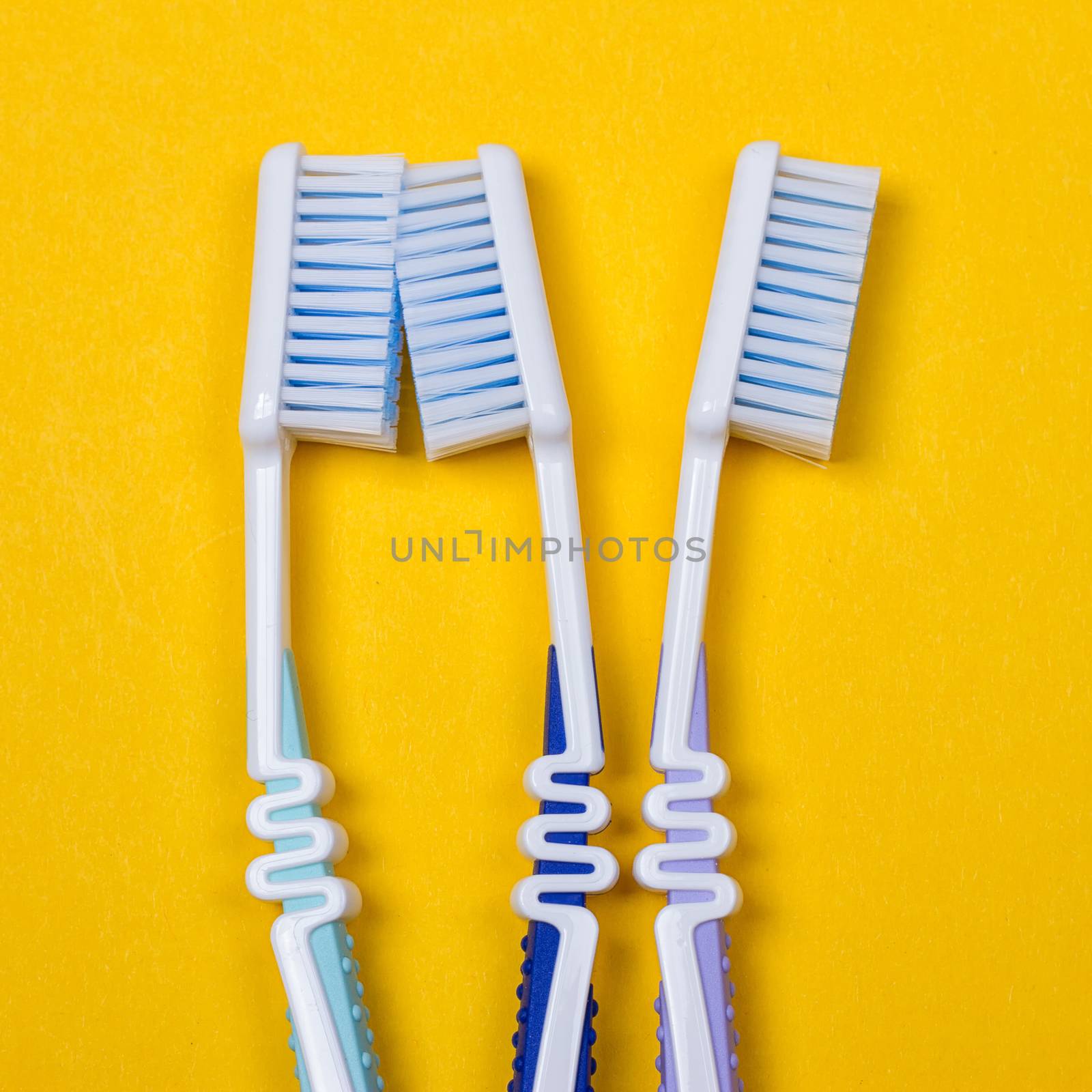 three Toothbrushes on the yellow background. Top view