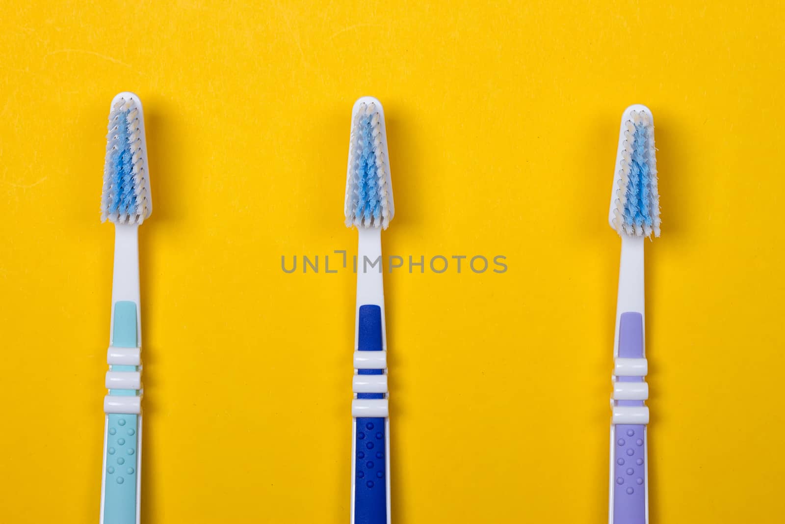 three Toothbrushes on the yellow background. Top view