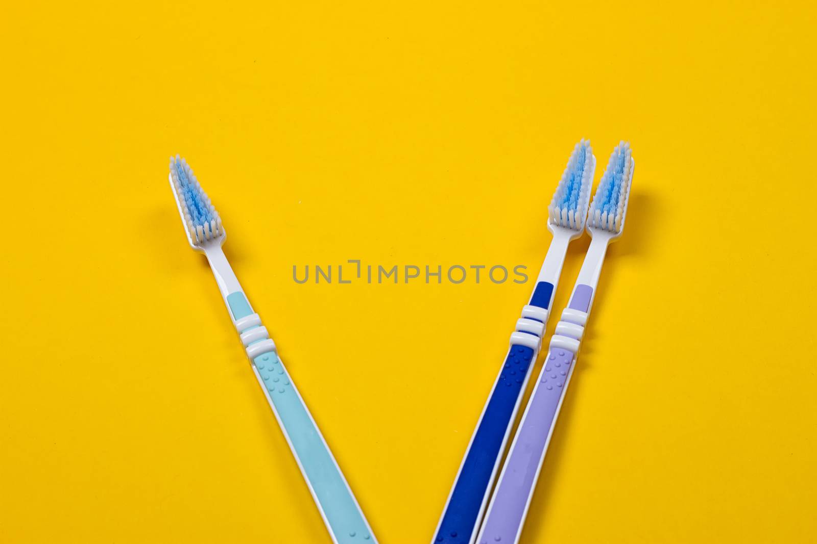 three Toothbrushes on the yellow background. Top view