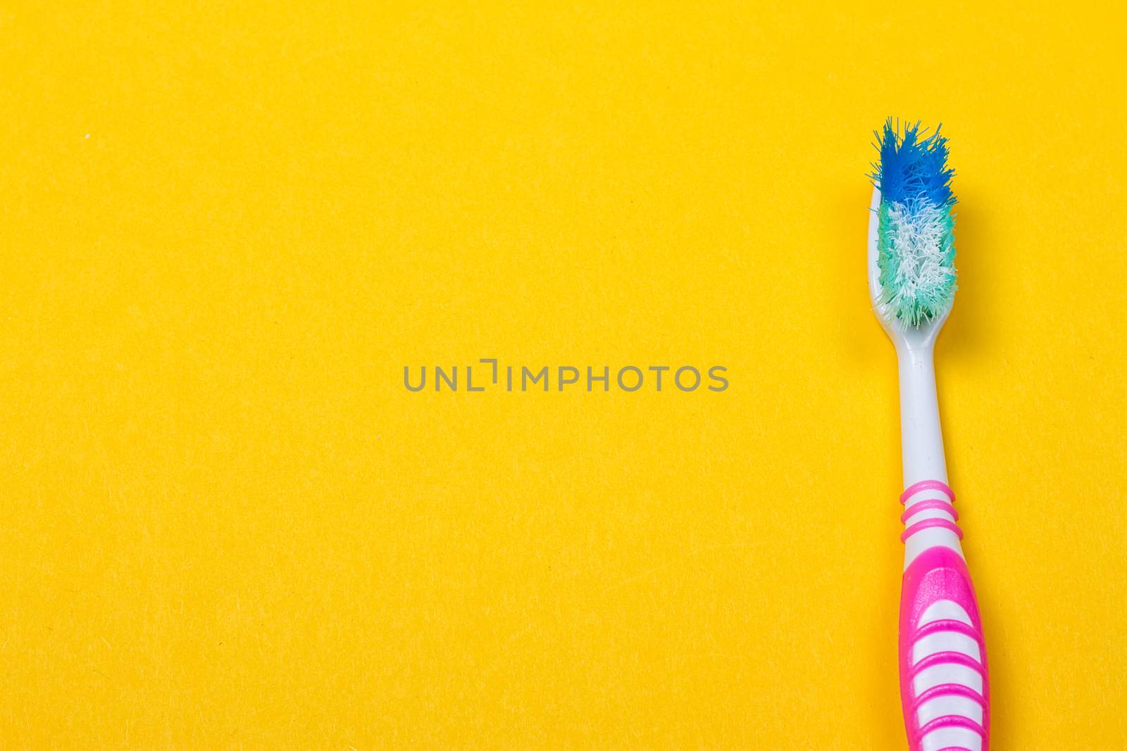 Old used toothbrush on the yellow background. Top view