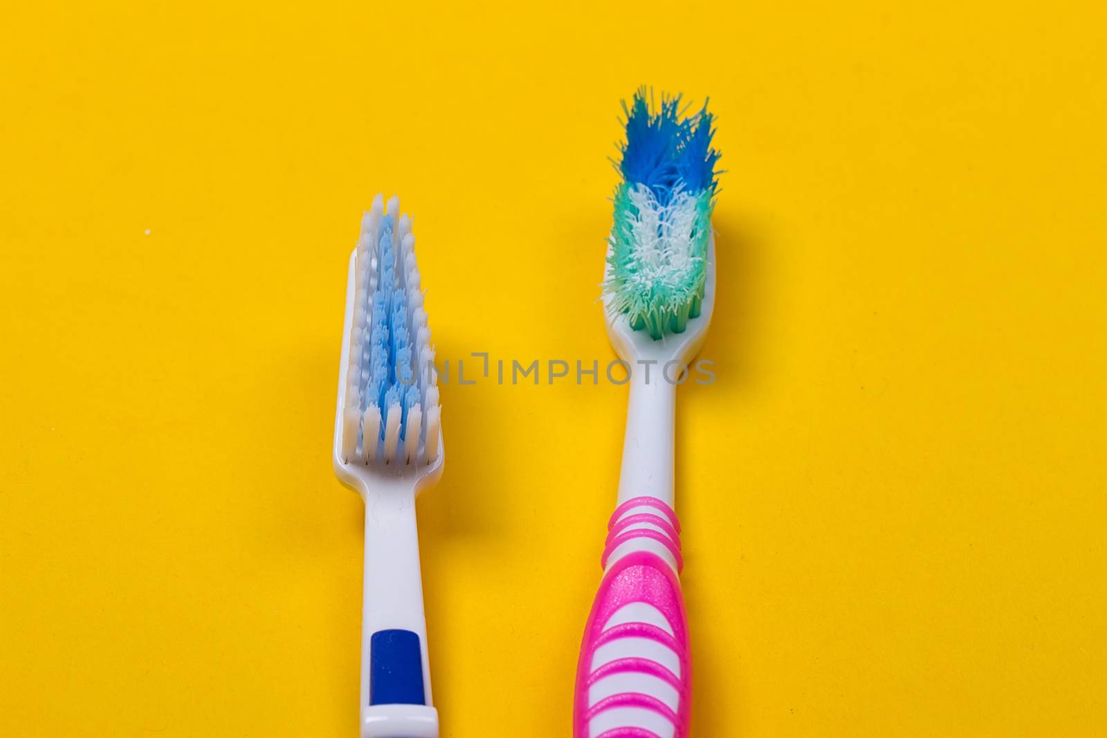 Old used and new toothbrushes on the yellow background. Top view