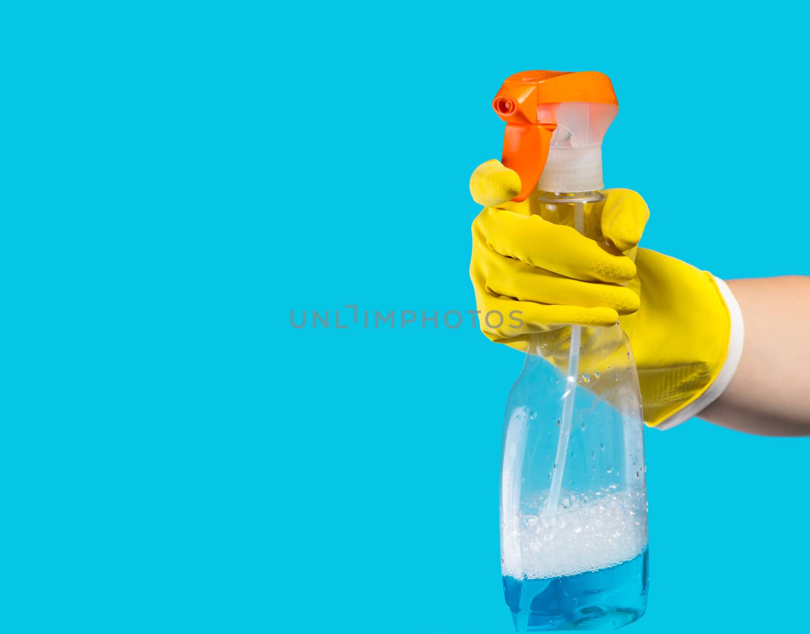 Detergent for cleaning in a female hand on blue background