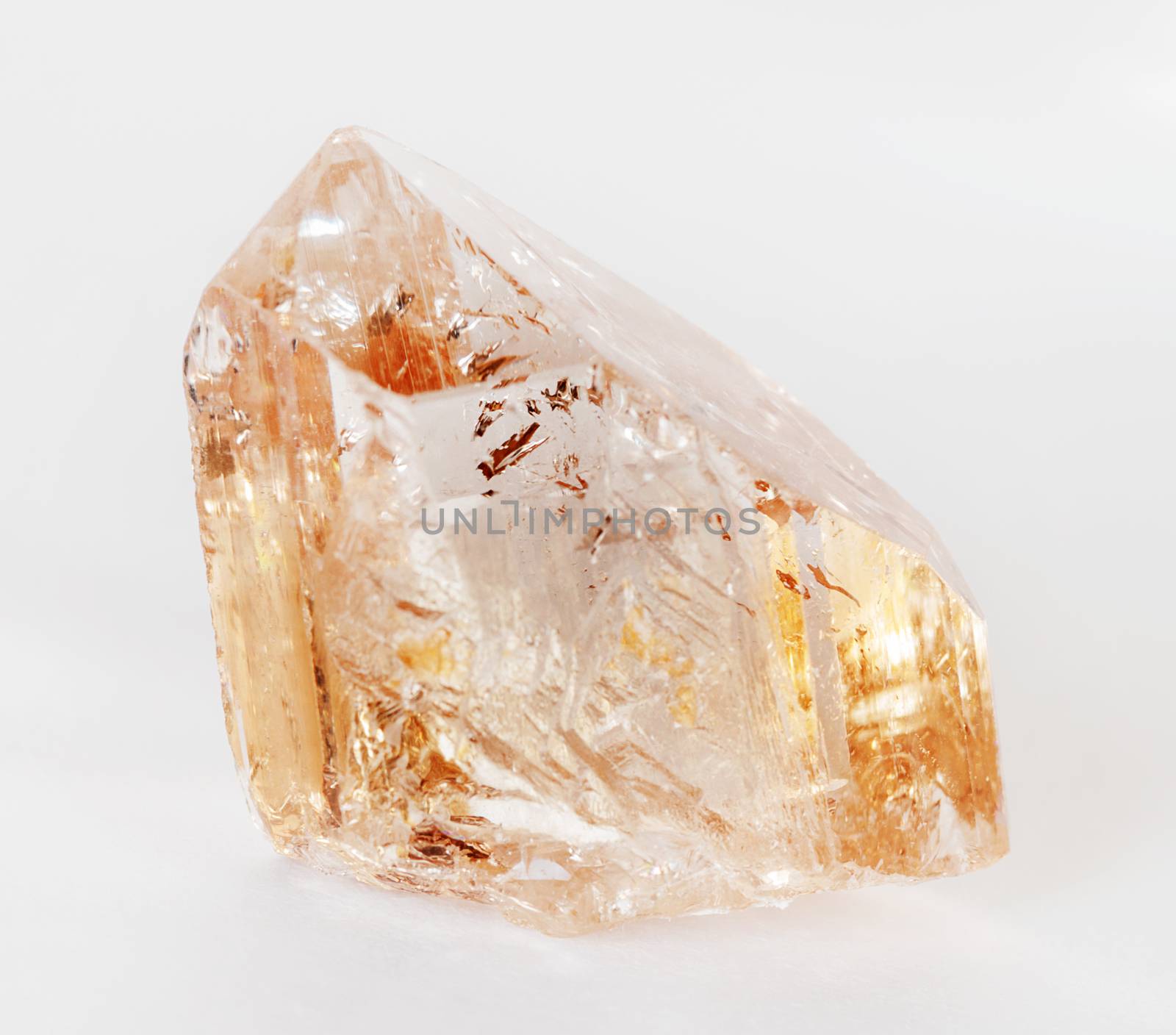 Natural crystal of clear precious wine topaz on a white background