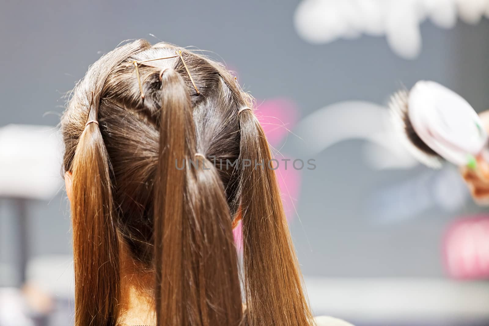 making coiffure with help of hair straightener, note shallow depth of field