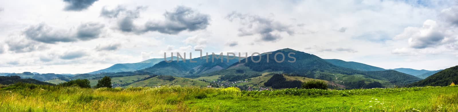 Summer landscape panoramic image of rural fields in mountains under cloudy sky