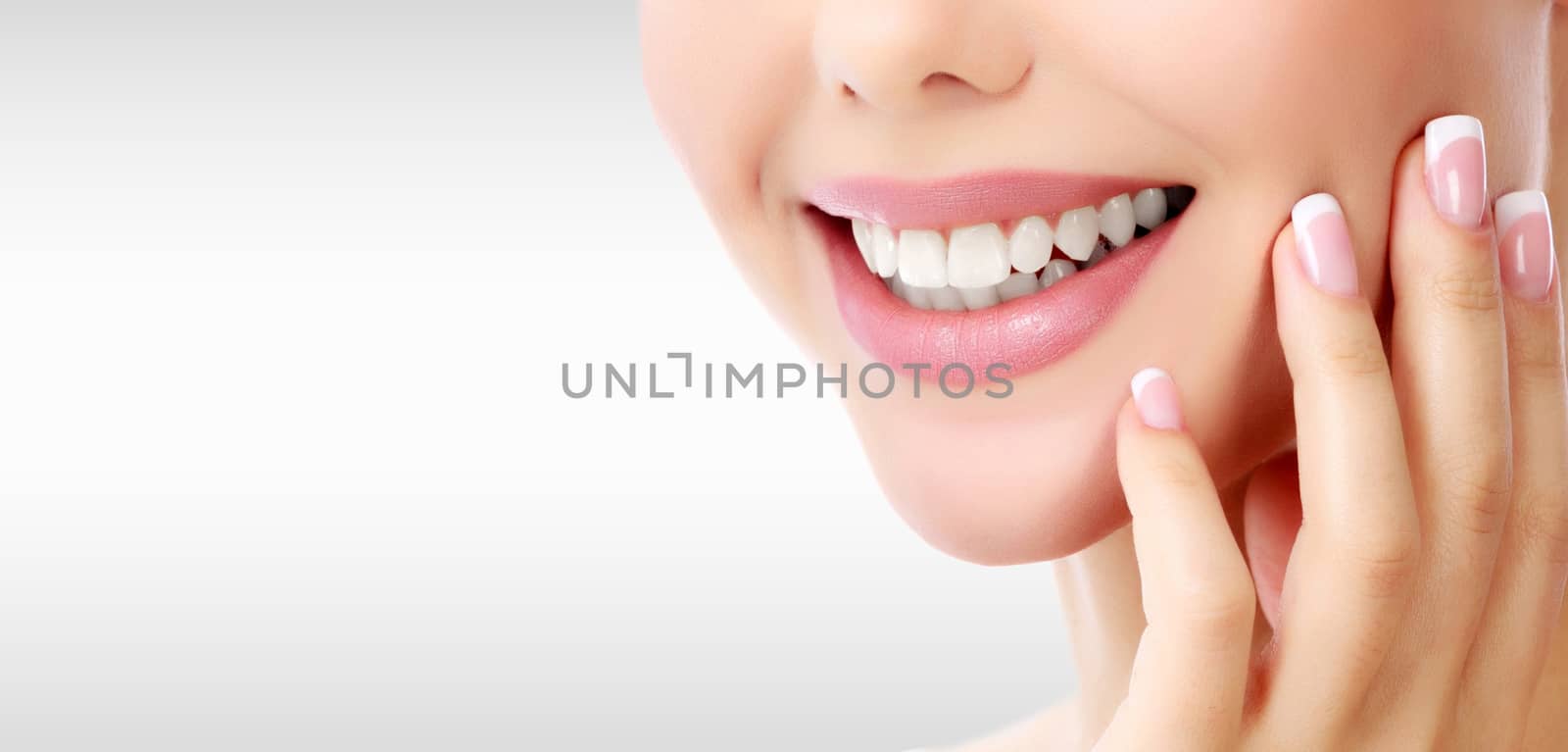 Closeup shot of woman's toothy smile against a grey background w by Nobilior