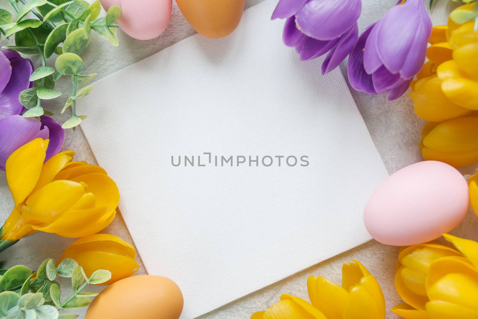 Easter card with blank white sheet surrounded by frame of yellow and purple crocus flowers and colorful Easter eggs