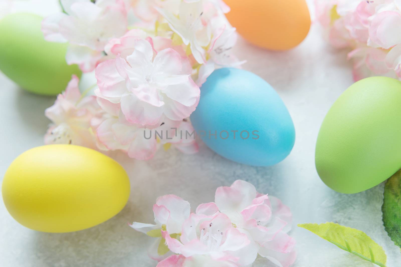 Beautiful delicate Easter composition with pink cherry flowers and multicolored Easter eggs on the stone background