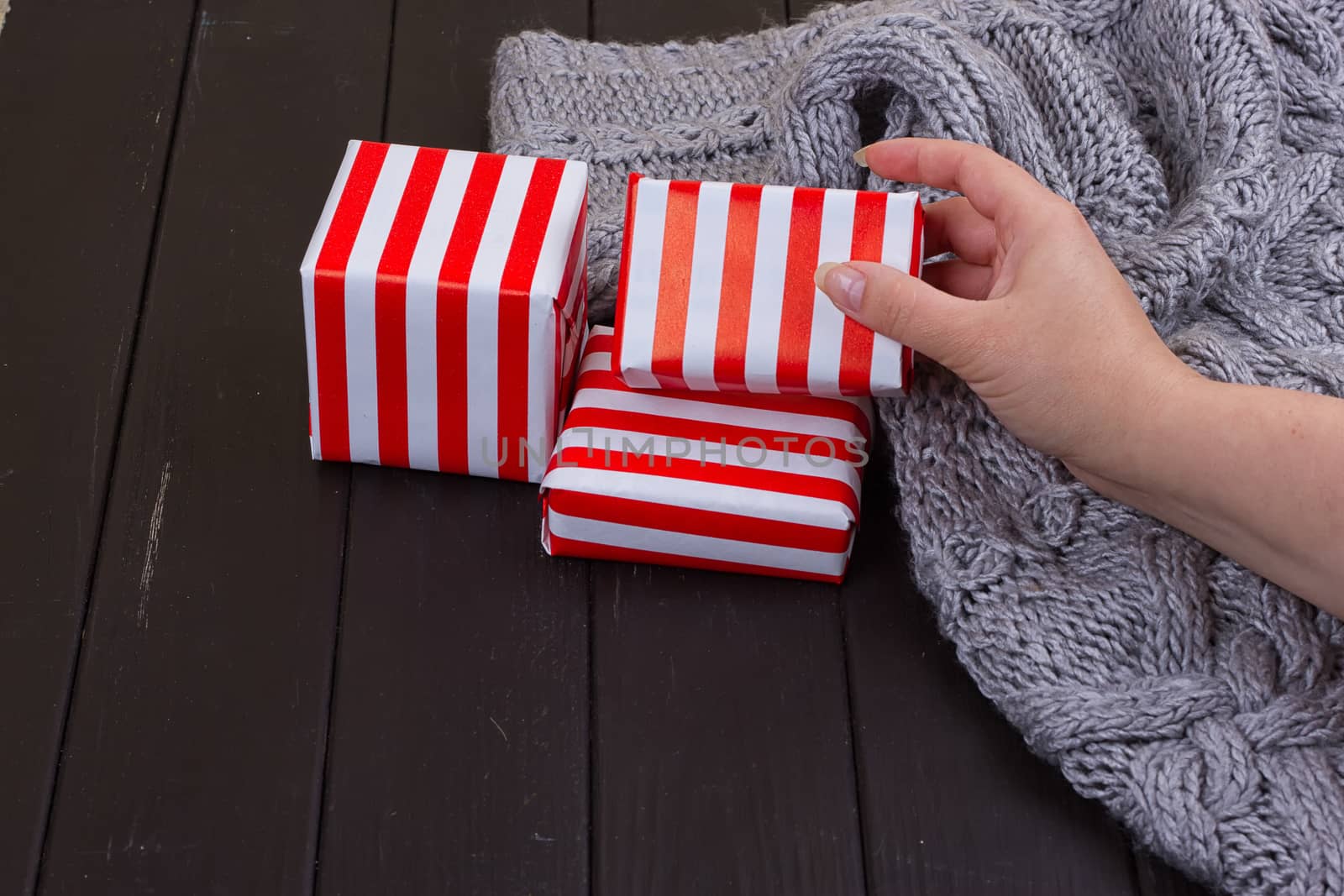 Christmas present. Woman's hands holding decorated gift box on rustic wooden table. Christmas or New year DIY packing.