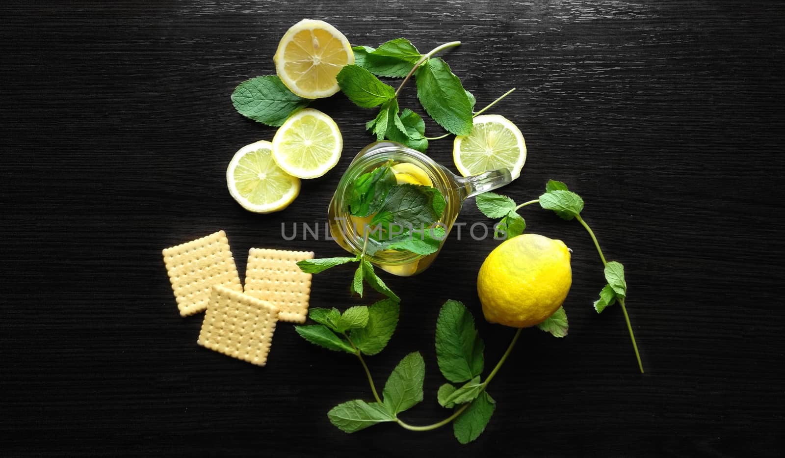 Mint herbal tea in glass cup with lemon on wooden background