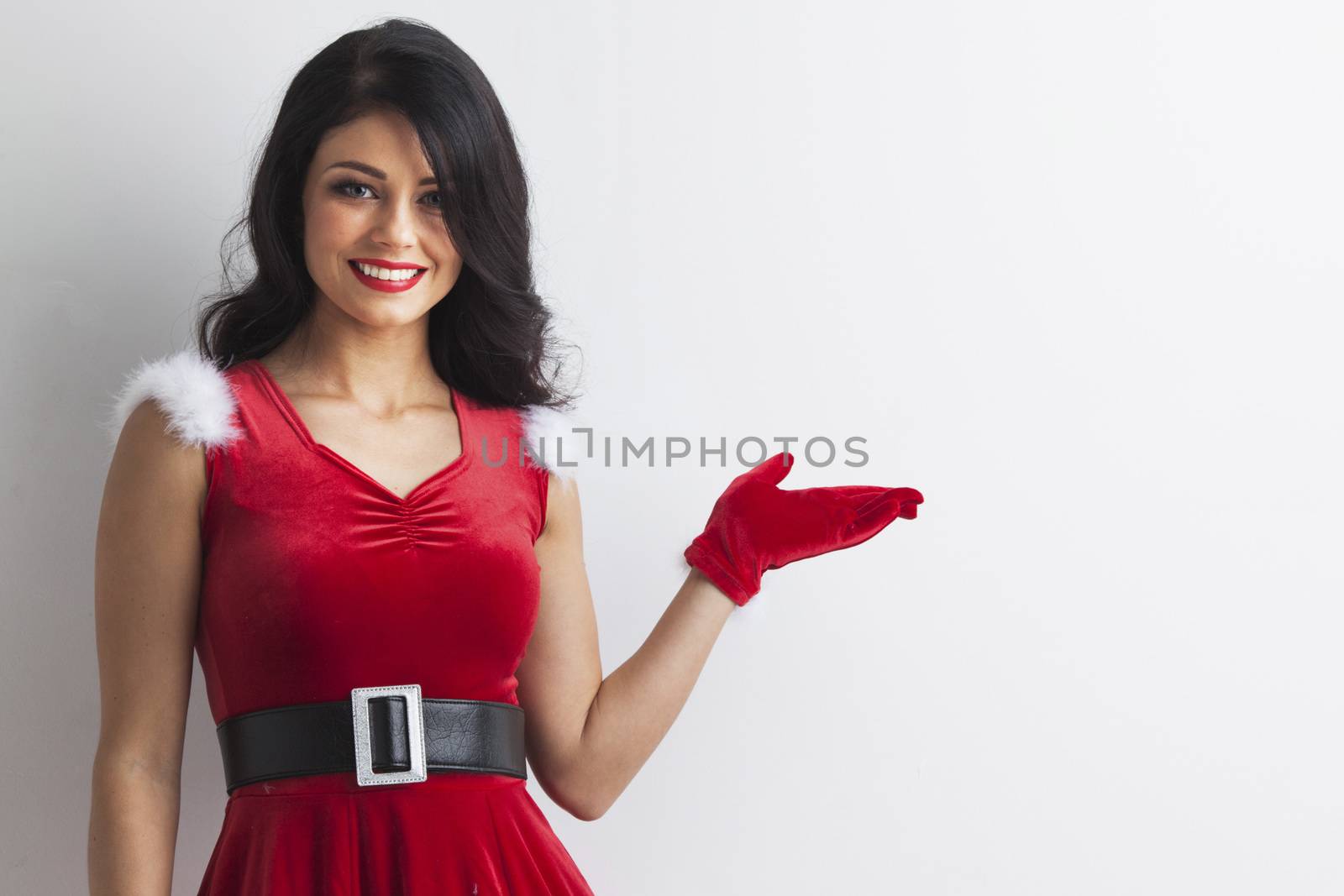 Young brunette christmas girl holding something on white background, copy space for text