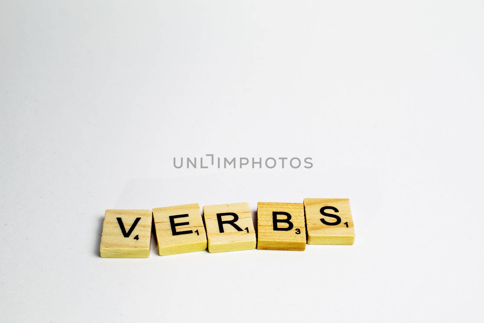 Scrabble tiles with word verbs written in a white background