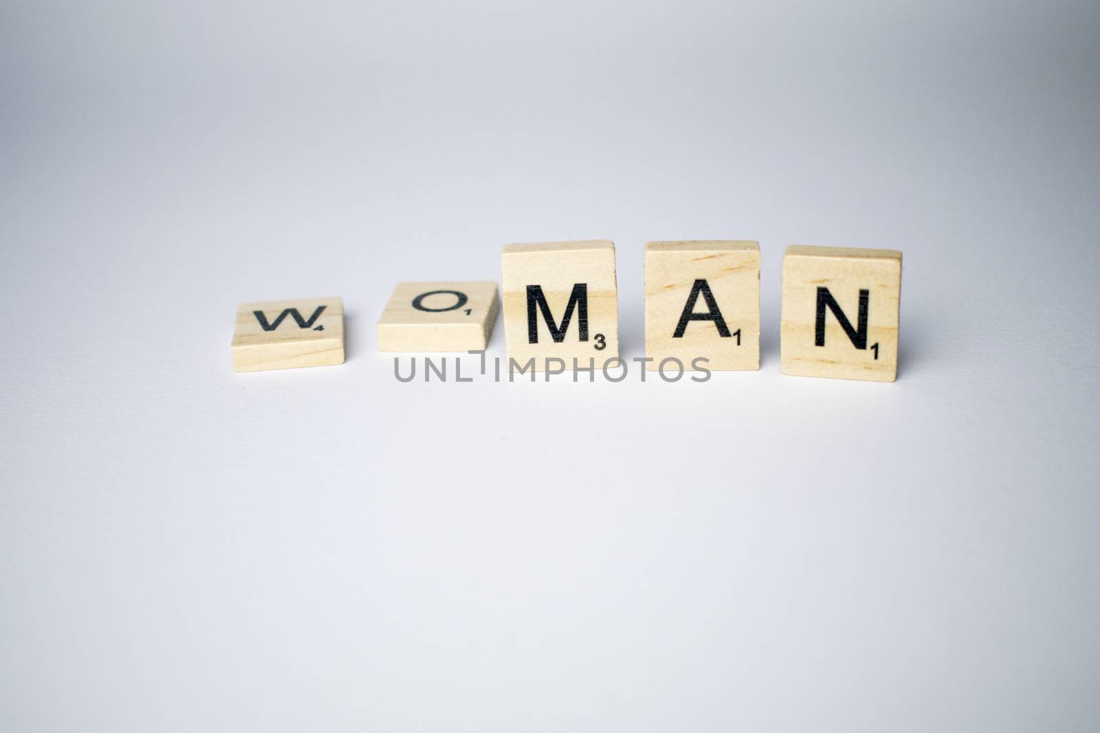 Scrabble tiles with word woman/man written on a white background to mind the differences between gender