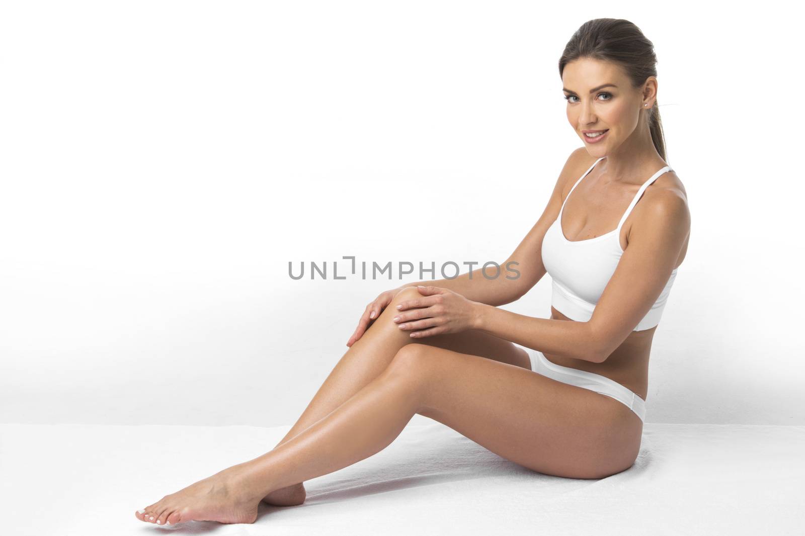 Young beautiful woman in cotton underwear sitting on white background
