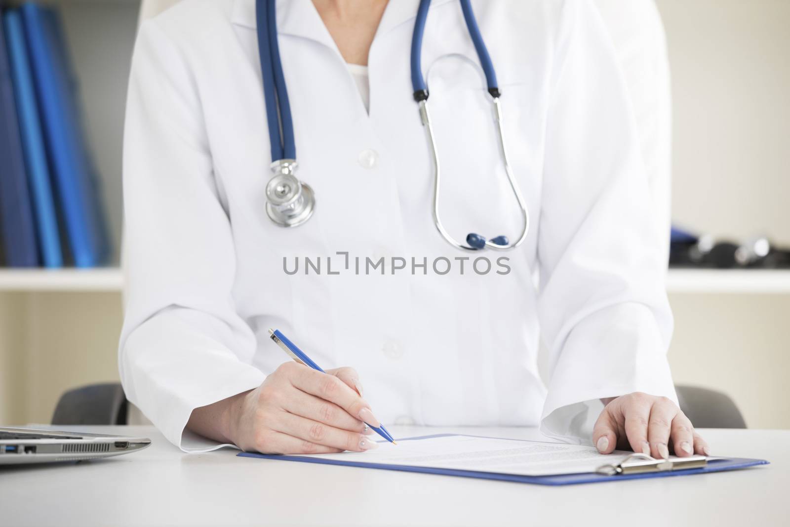 Doctor in a white labcoat writing out RX prescription