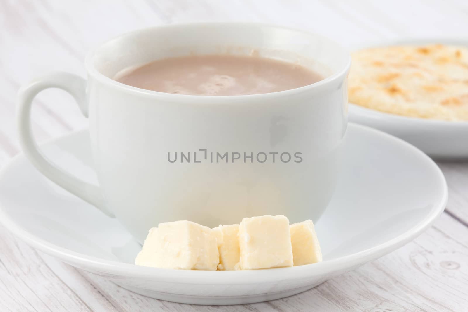 Cup of hot chocolate with cheese and arepa served in white dishware