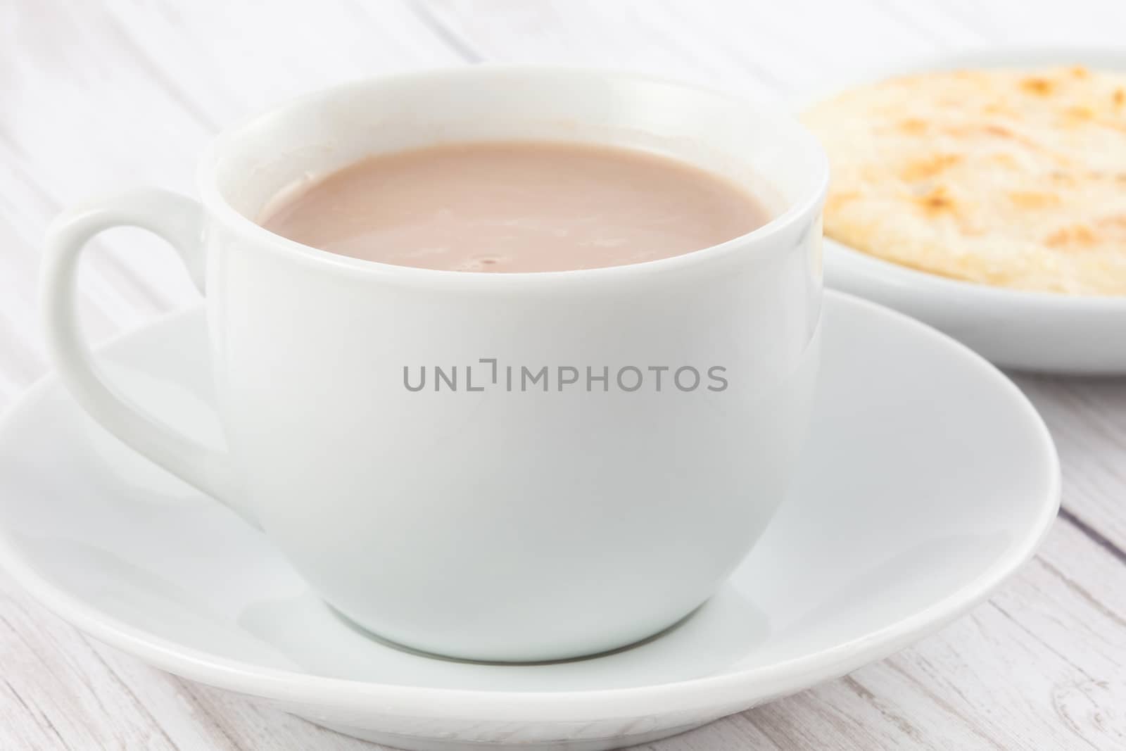 Cup of hot chocolate with cheese and arepa served in white dishware