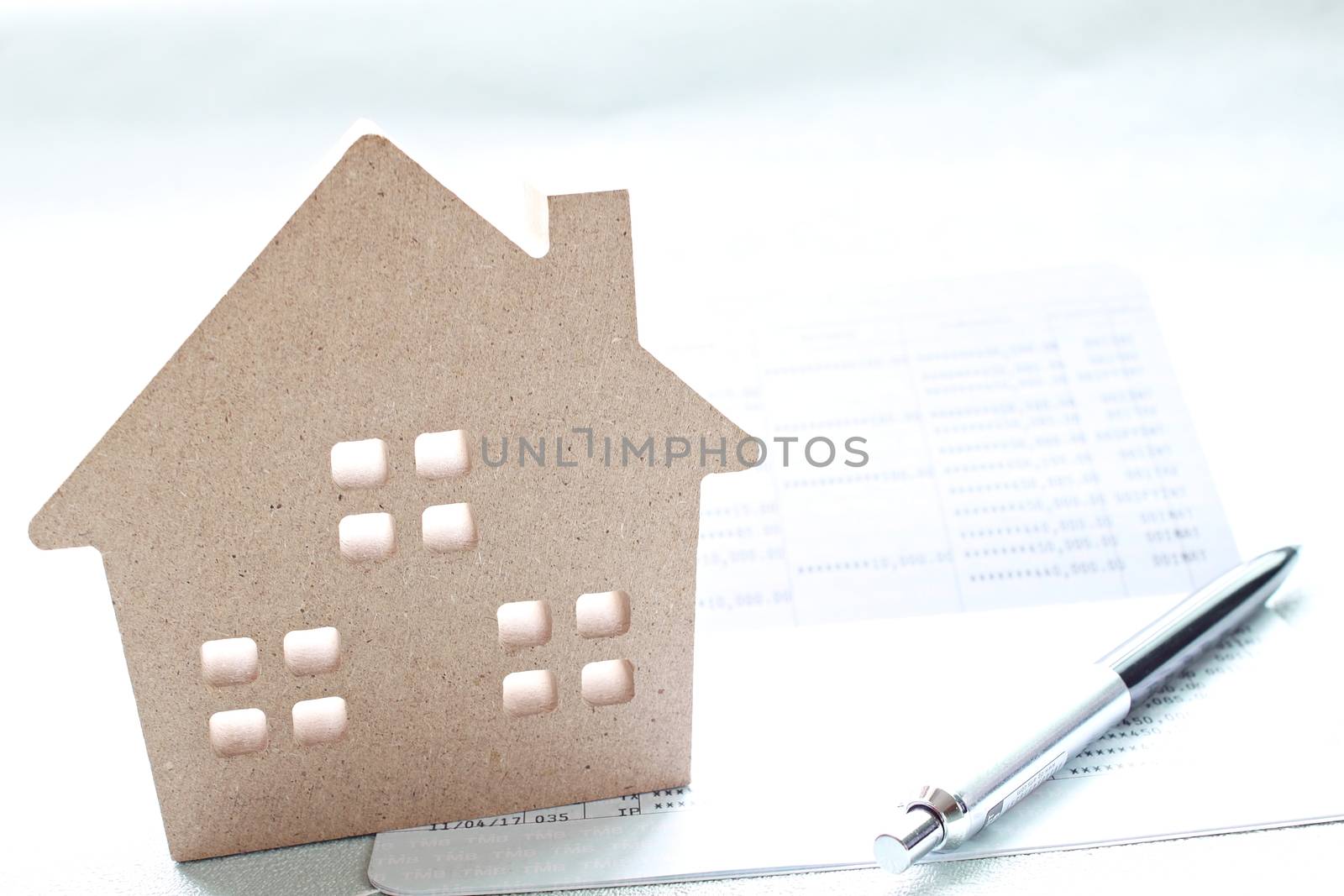 Business, finance, saving money, banking, property loan or mortgage concept :  Wood house model, saving account book or financial statement and coins scattered from glass jar on office desk table