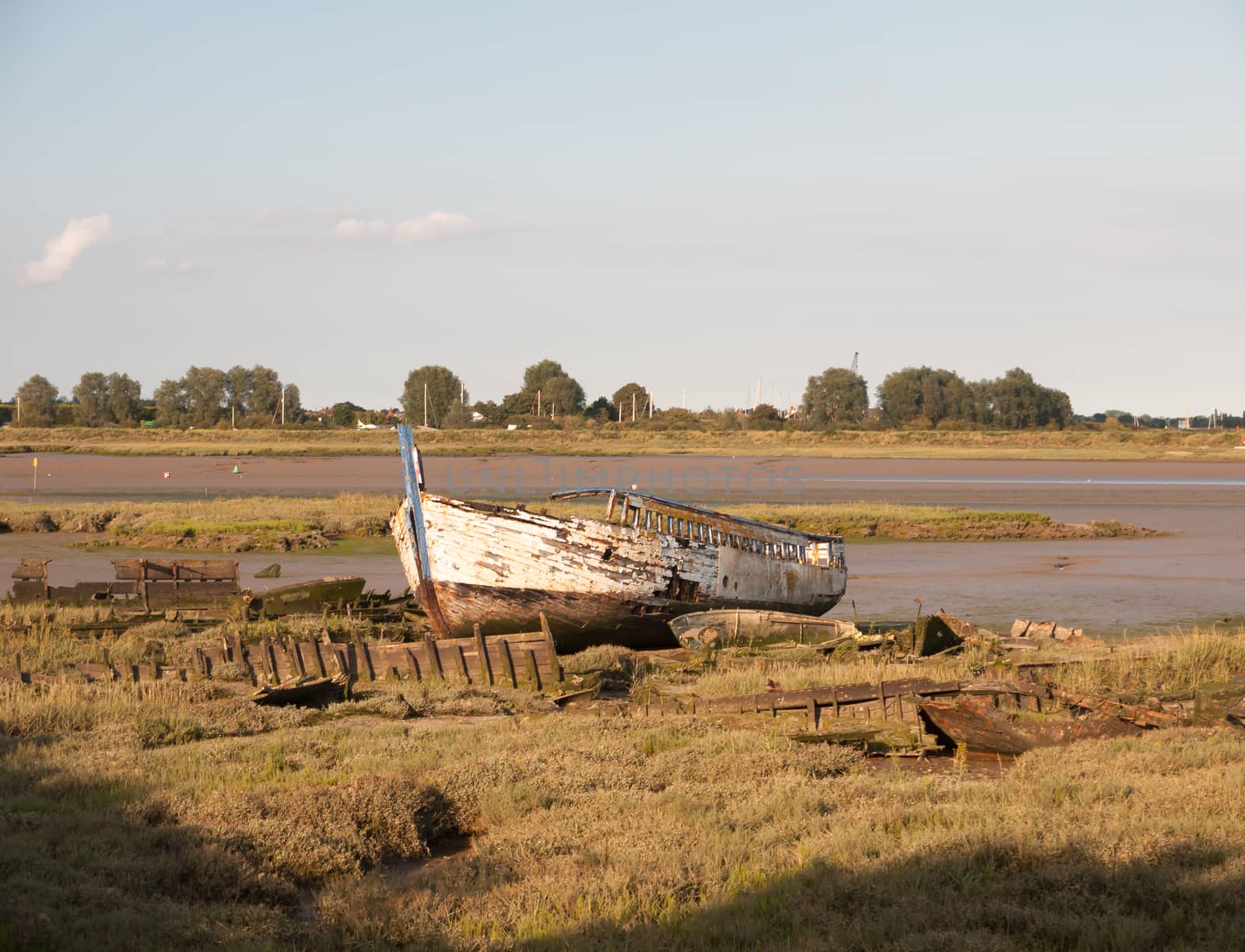 moored old rusted white wooden boat big in the sun light at edge of river black water Maldon;Essex; England; UK