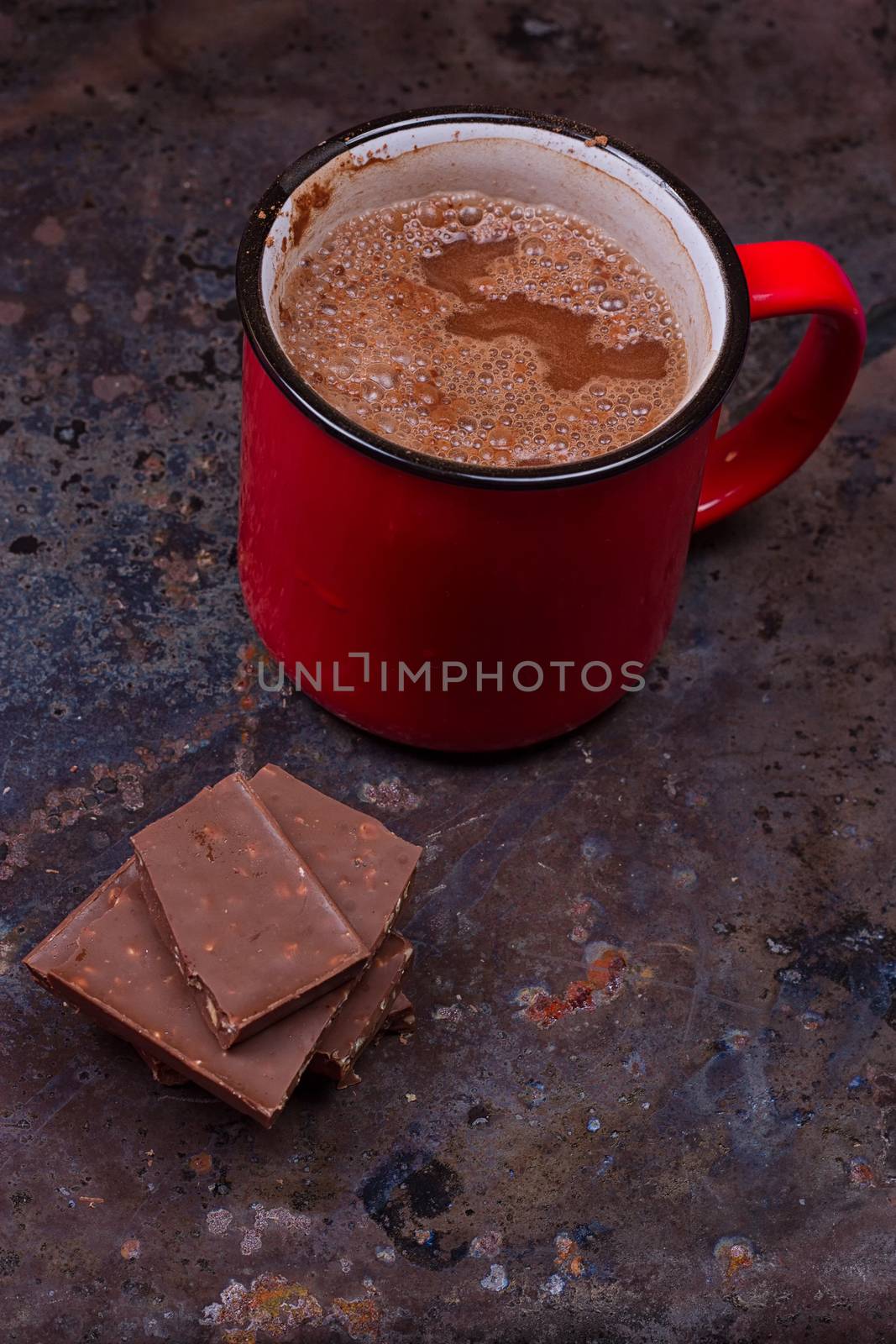 Hot chocolate in mug with chocolate on grunge dark table